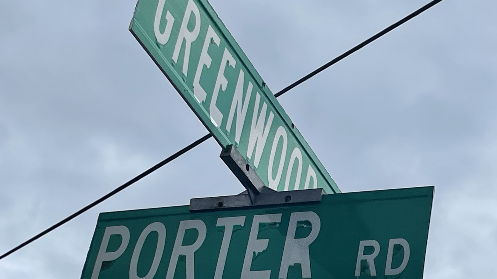 Stop sign with intersecting green street signs on top saying Porter and Greenwood.