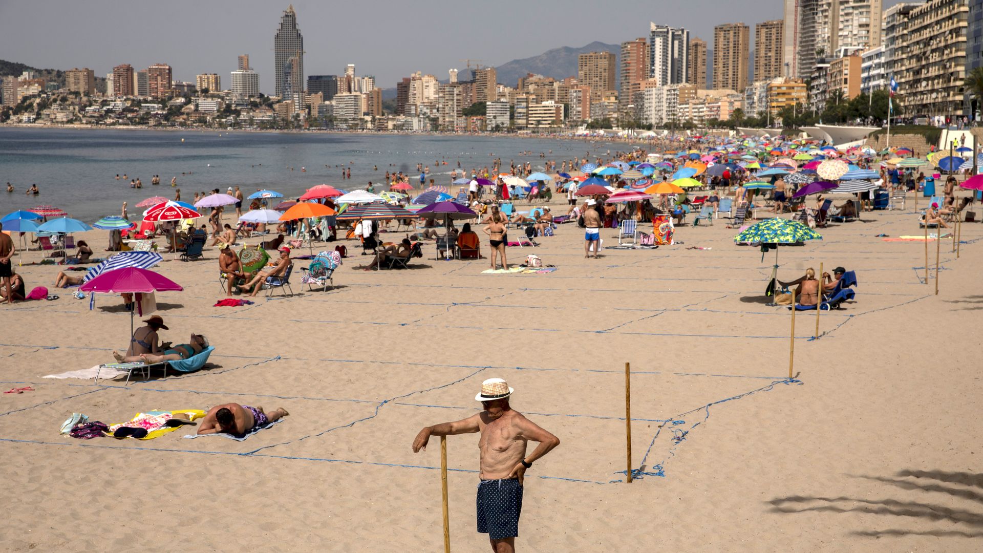 A man stands on a crowded beach.