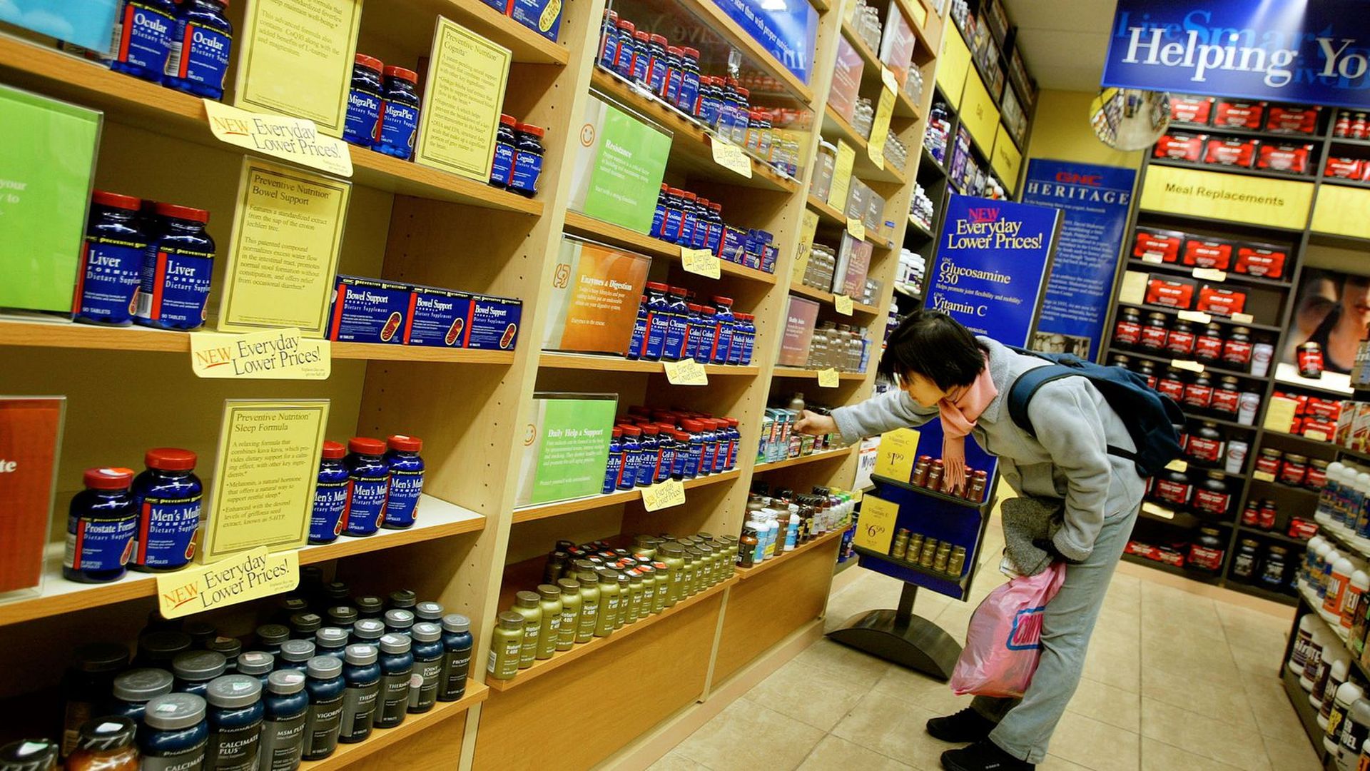 A shopper looks through shelves of supplements.