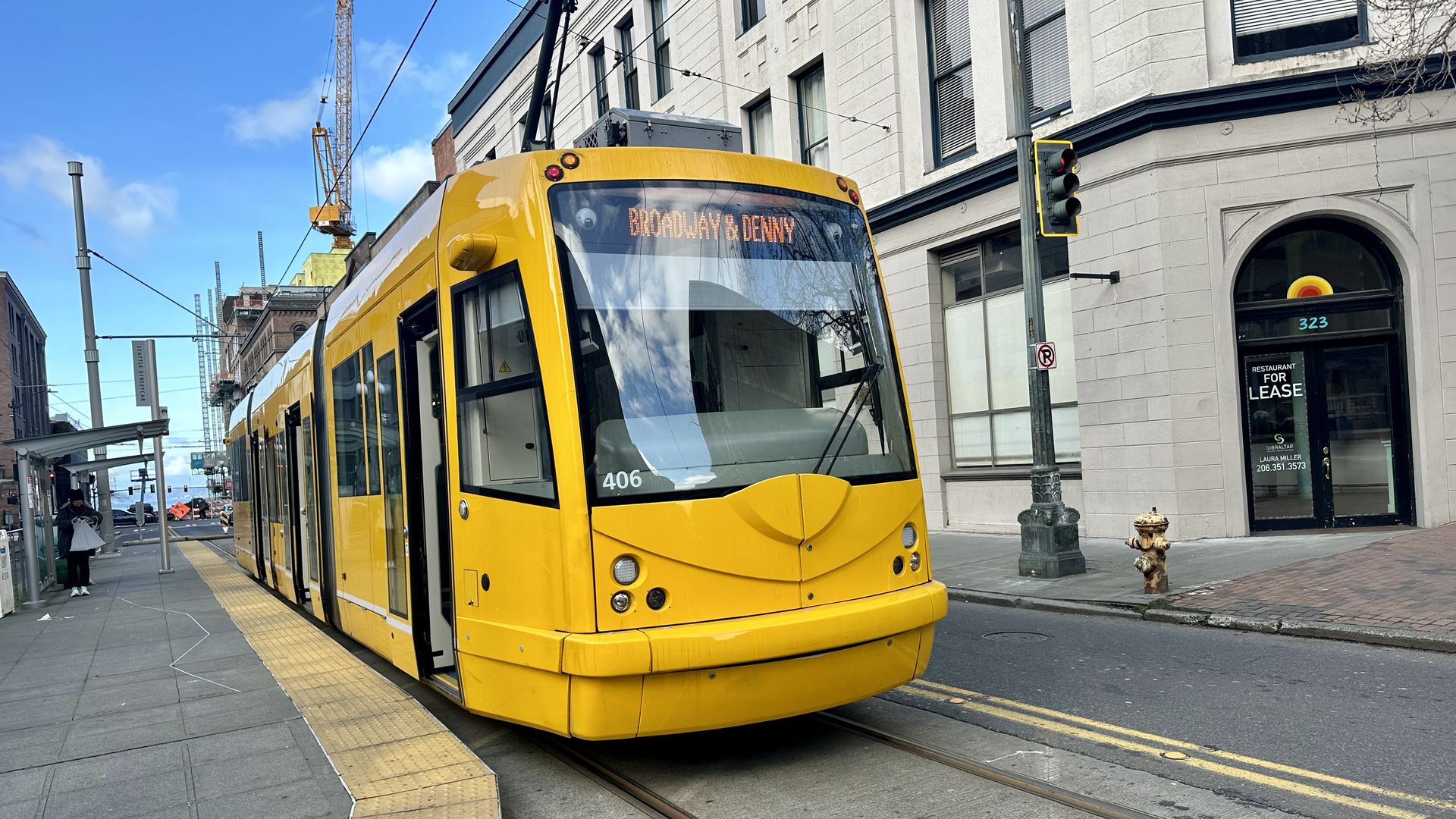 A yellow streetcar runs along a track with an older building in the background. 