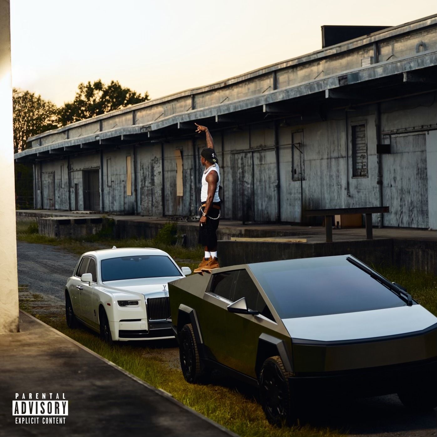 DaBaby stands on a Cybertruck with a Rolls-Royce behind him