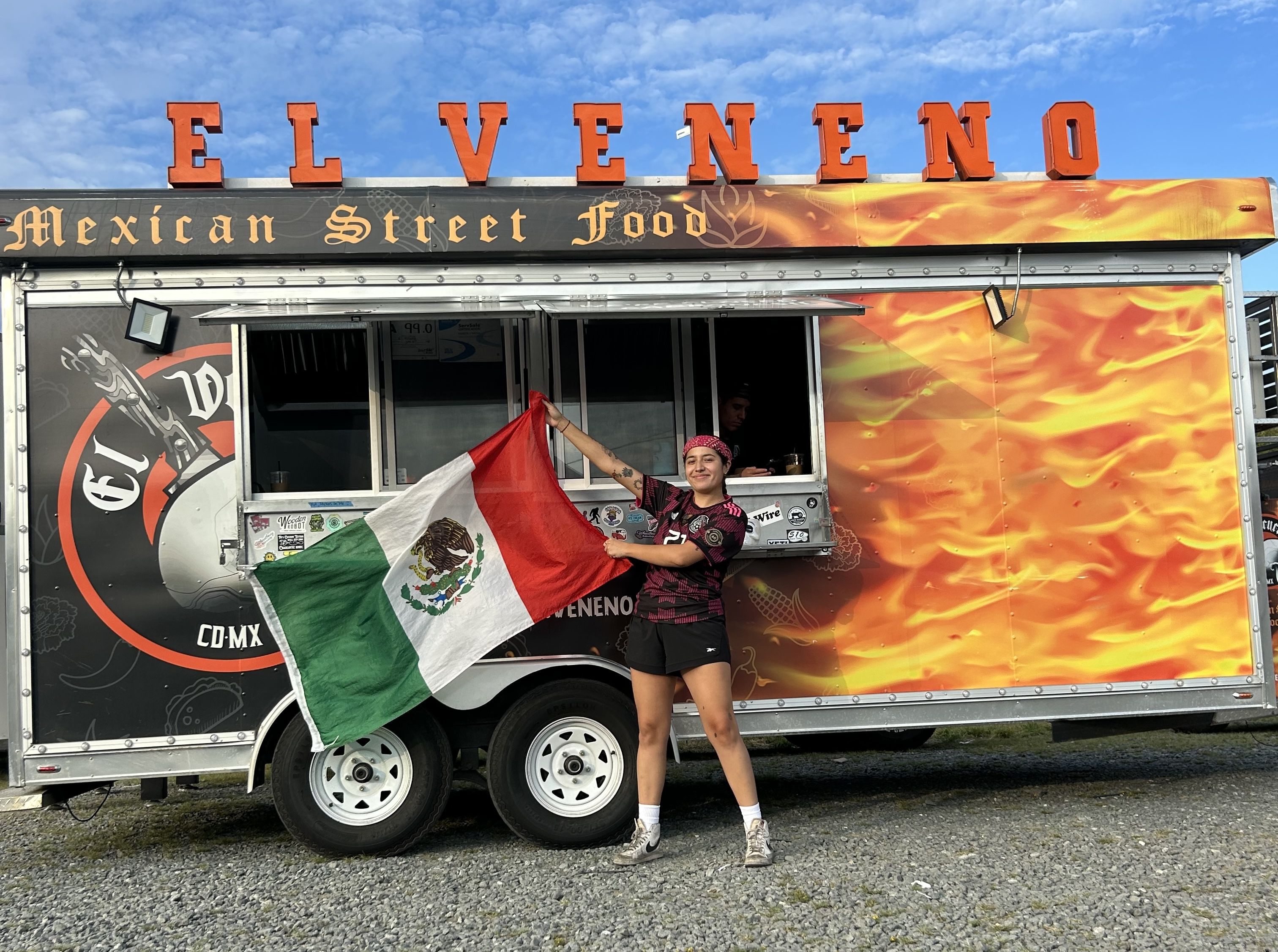 person standing in front of food truck with Mexican flag