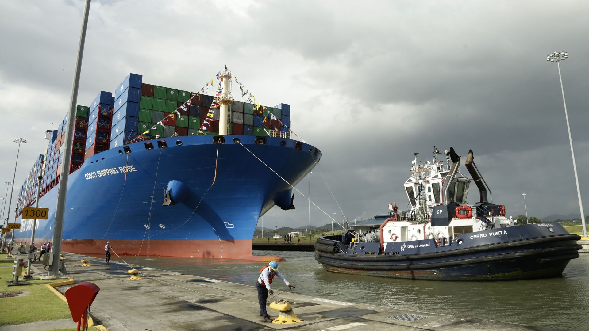 In this image, a dock worker at the Panama canal docks a huge shipping container that sits on the water. 