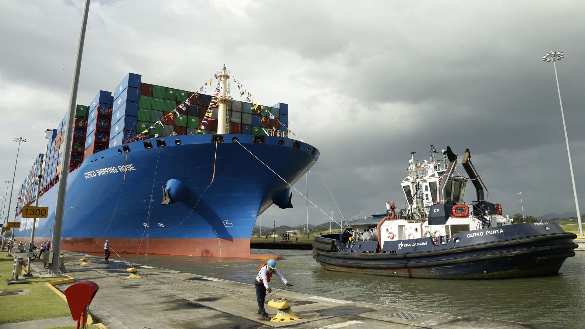 In this image, a dock worker at the Panama canal docks a huge shipping container that sits on the water.