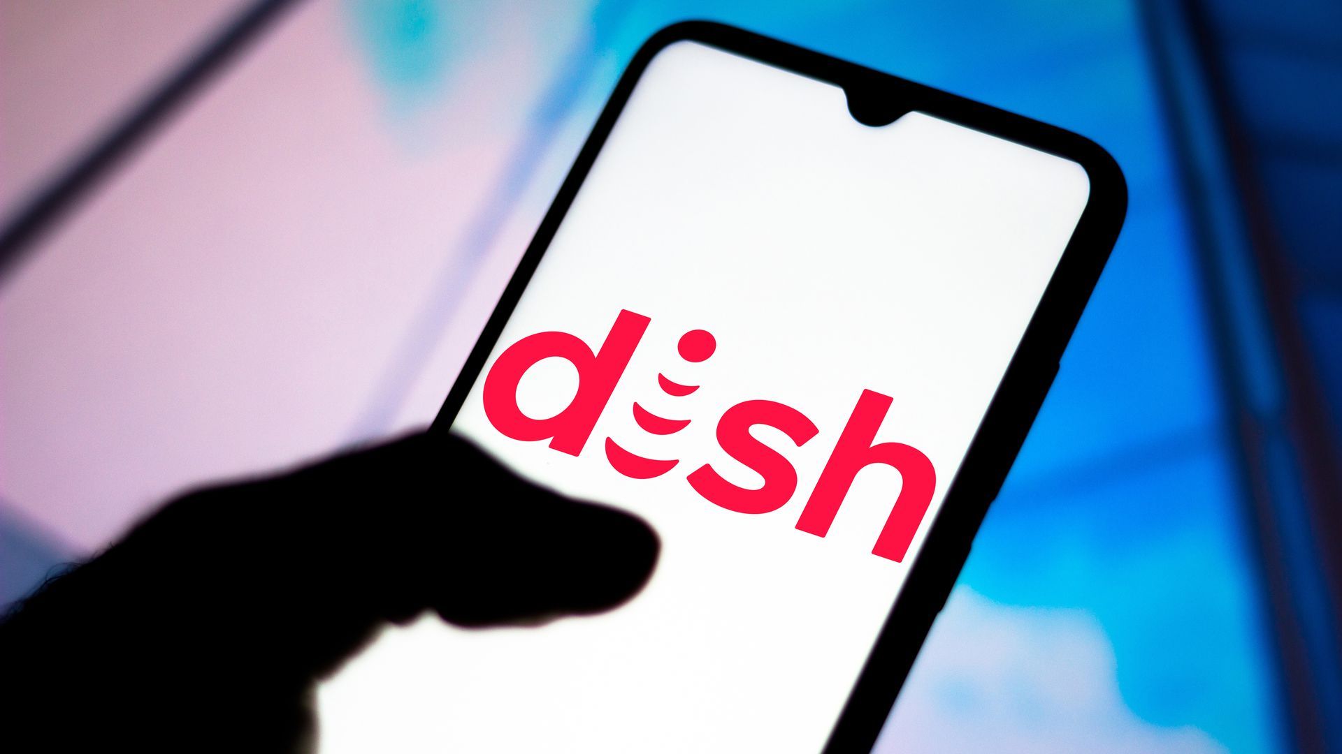A photo illustration of a hand holding a smartphone with the Dish Network logo on its screen.