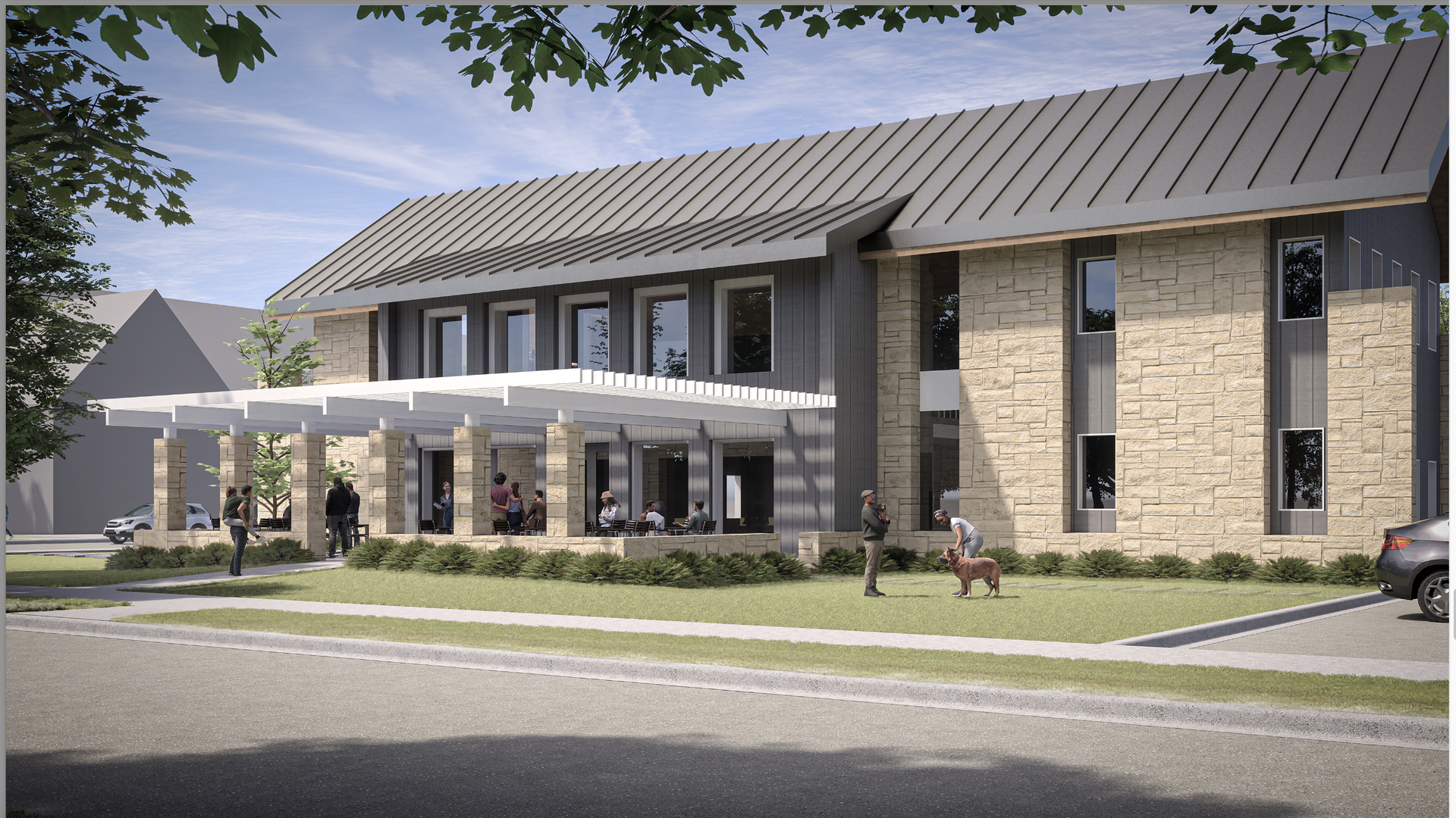 Modern two-story building with stone and dark panel exterior, a metal sloped roof, and a white pergola-covered patio. People gather outside, one bends to pet a dog on grass.