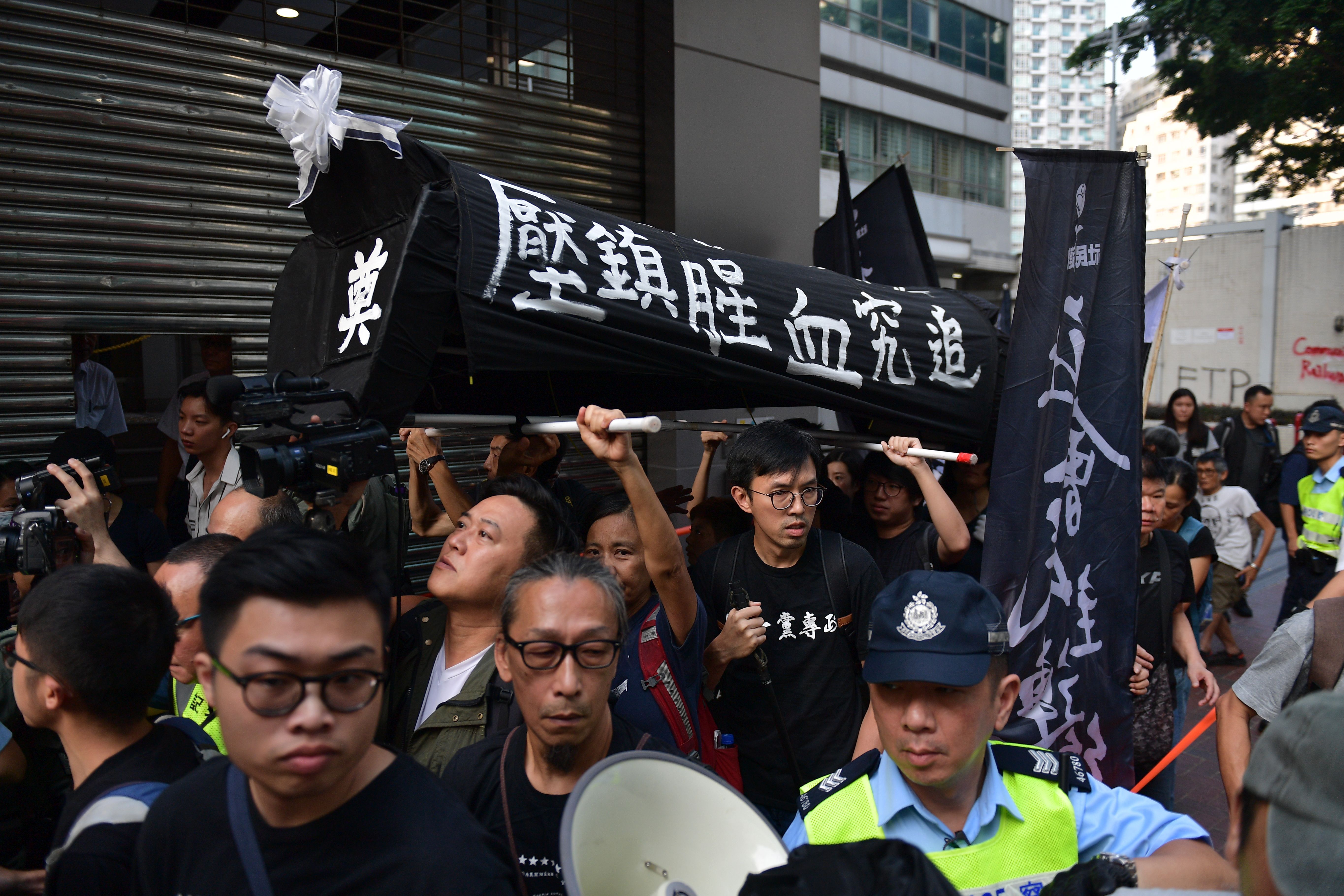 Protesters carry a mock coffin early morning in the Wanchai district in Hong Kong 