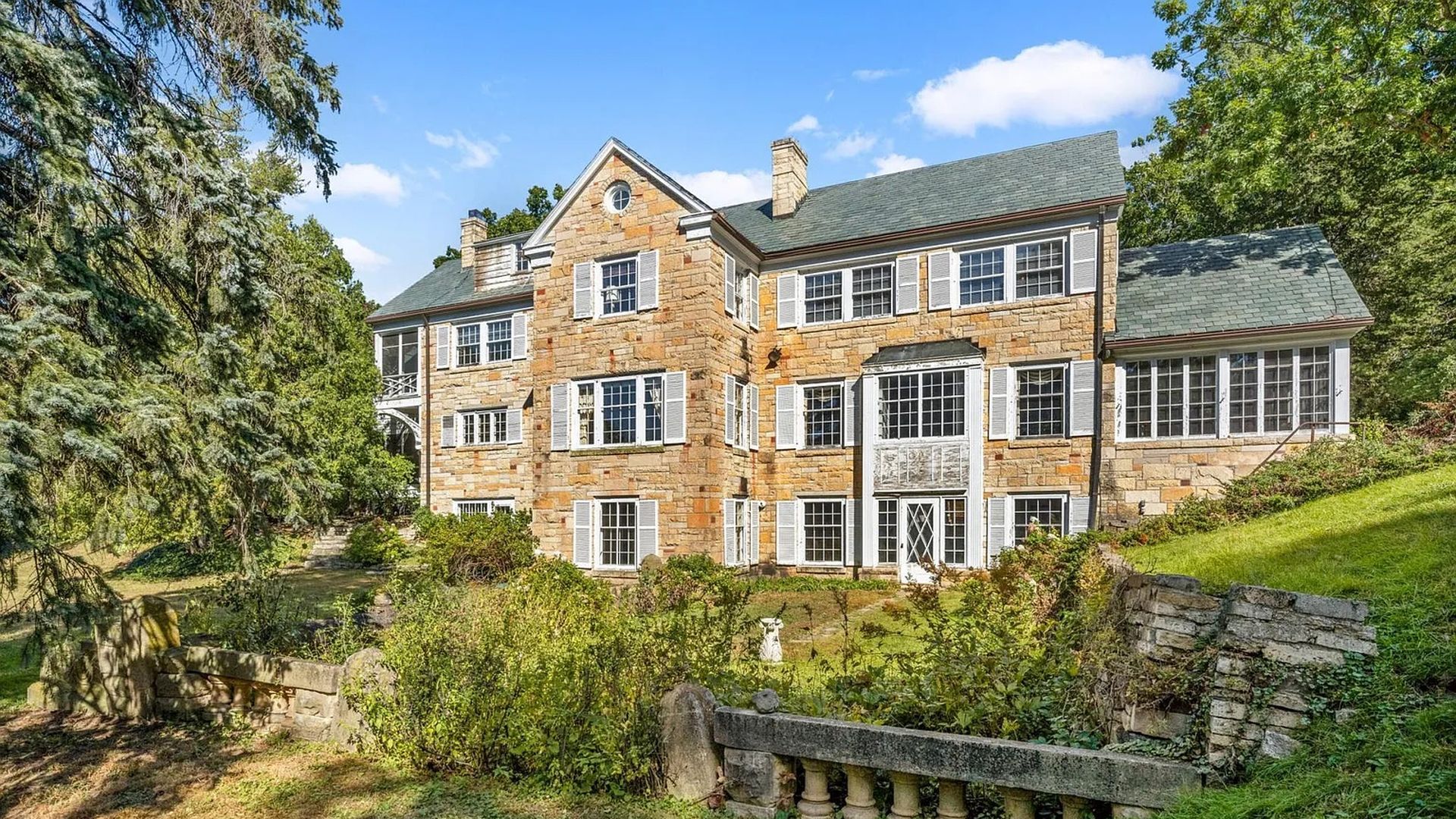 A three-story mansion with a gray roof and brown stone.