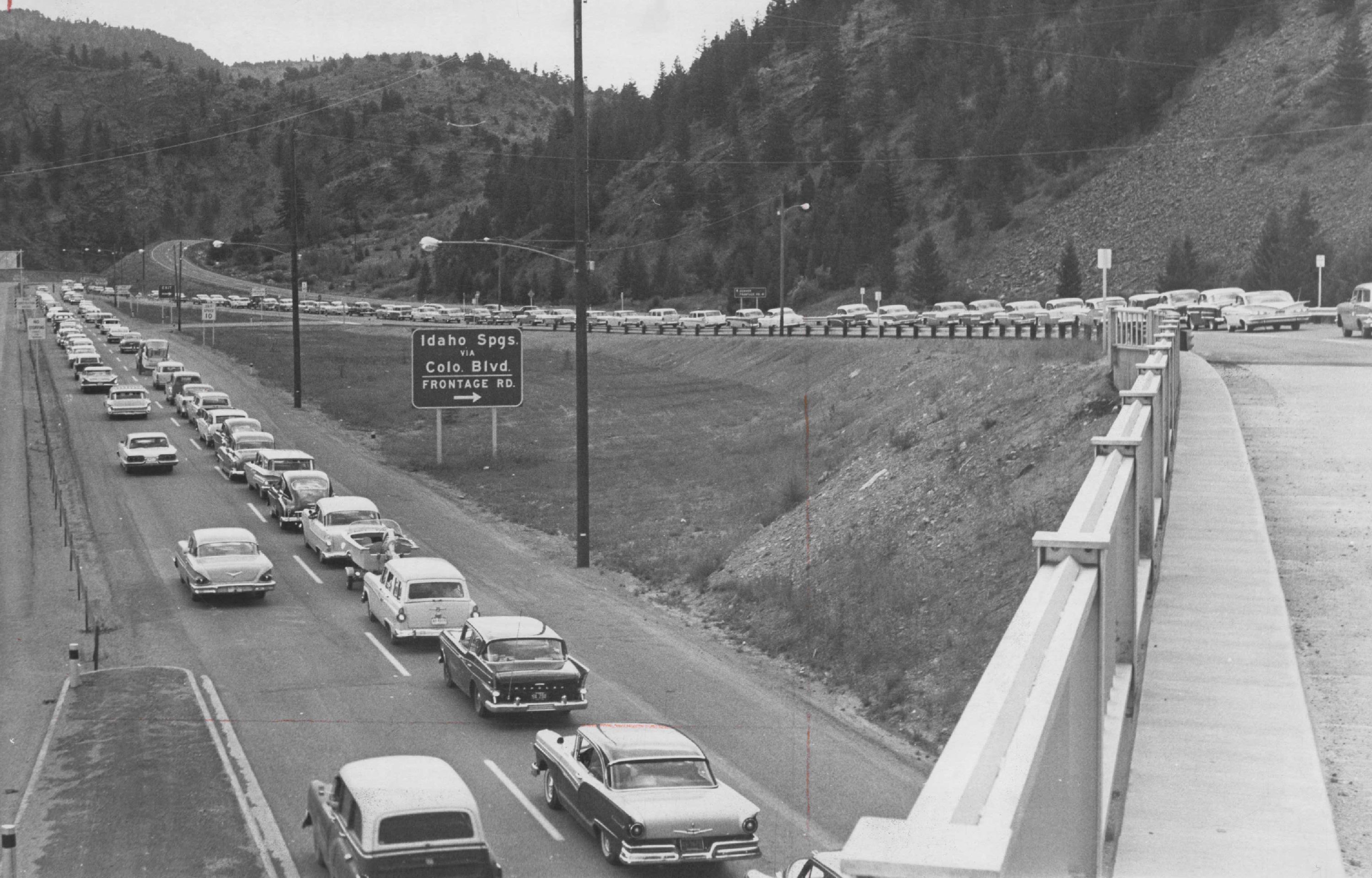 A black and white photo of old-timey cars in traffic on the highway.