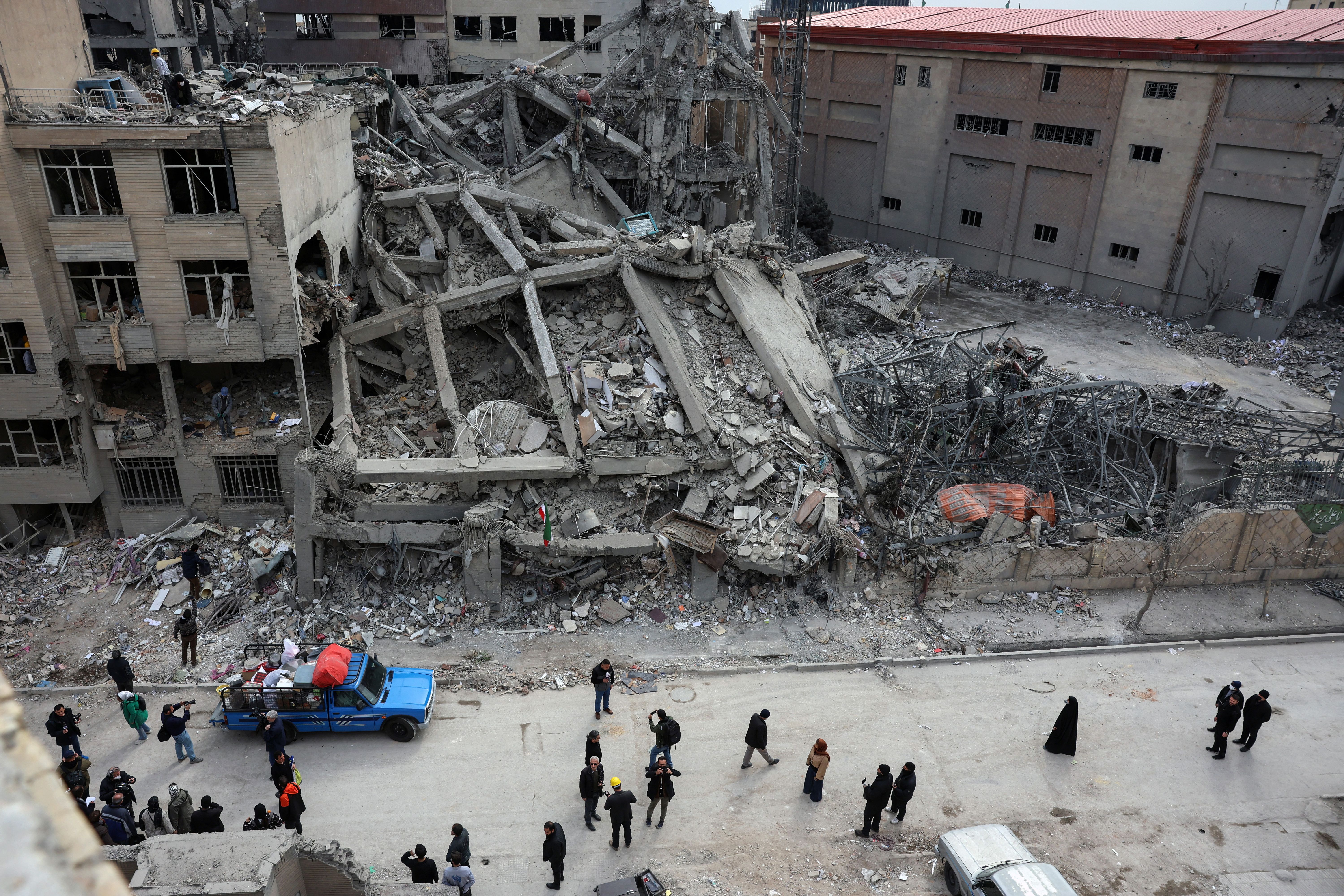 Iranians gather next to a damaged residential building as they collect belongings from the rubble in Tehran on March 12, 2026.