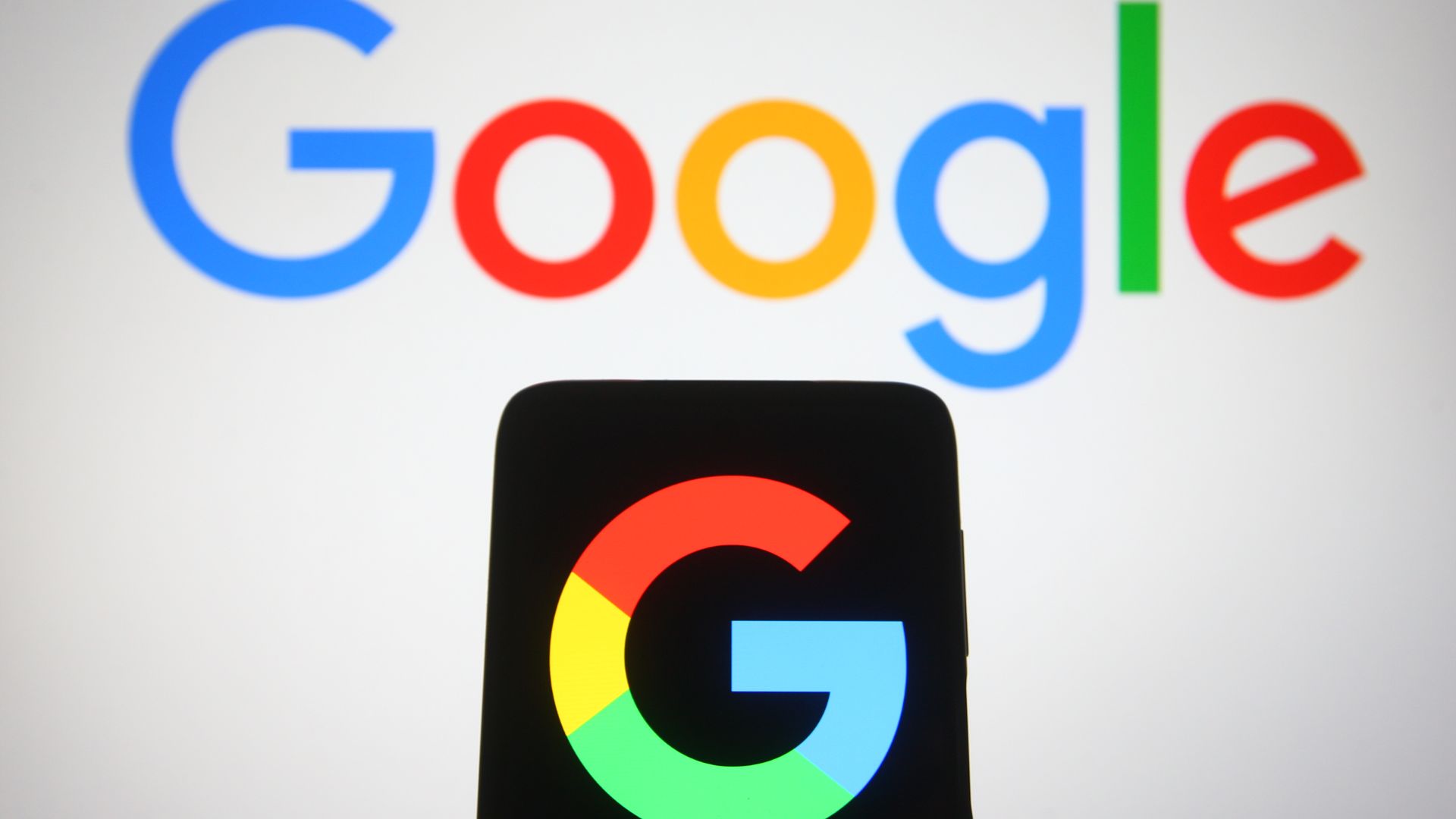 A Google logo seen displayed on a smartphone and a pc screen.