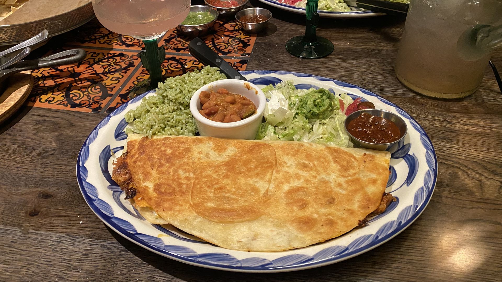 A quesadilla with cilantro rice and boraccho beans on a plate at El Segundo, next to a margarita glass
