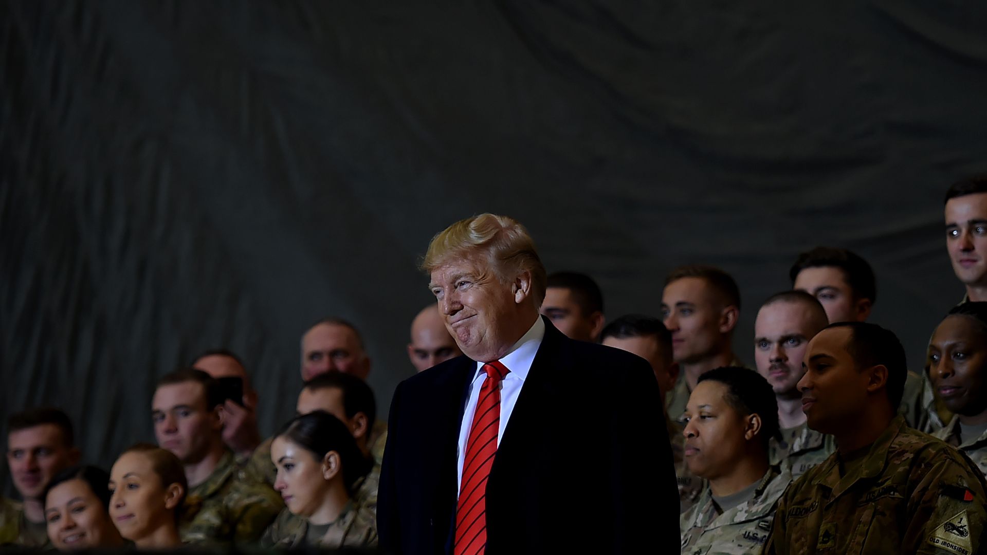 In this image, Trump stands in front of a few rows of soldiers.