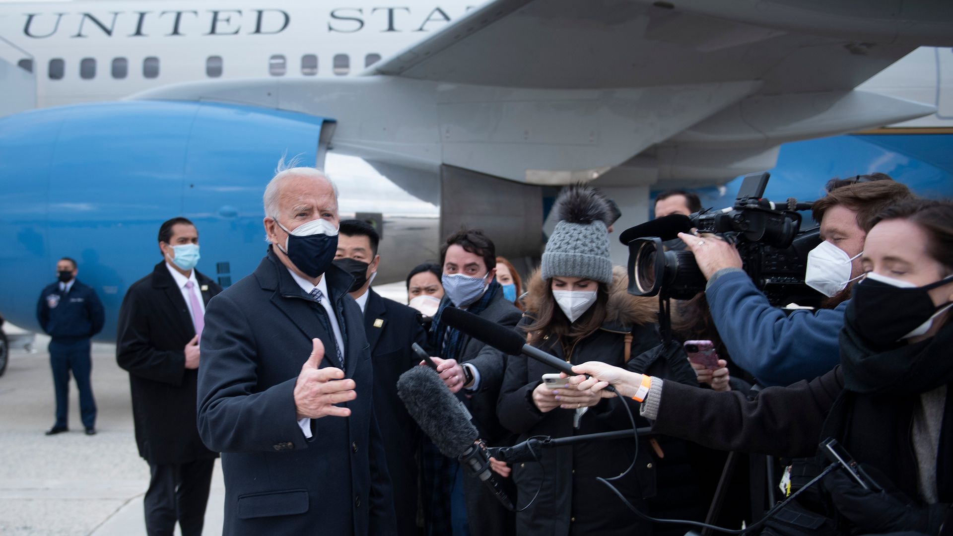President Biden is seen speaking with reporters assembled under the wing of Air Force One.