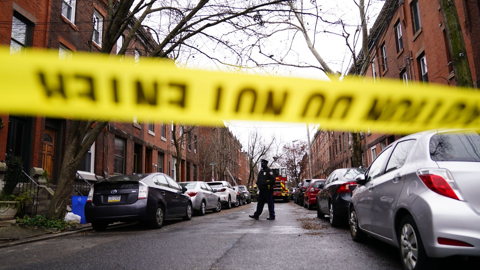 A police officer stands in focus behind an out-of-focus caption tape in Philadelphia's Fairmount neighborhood.