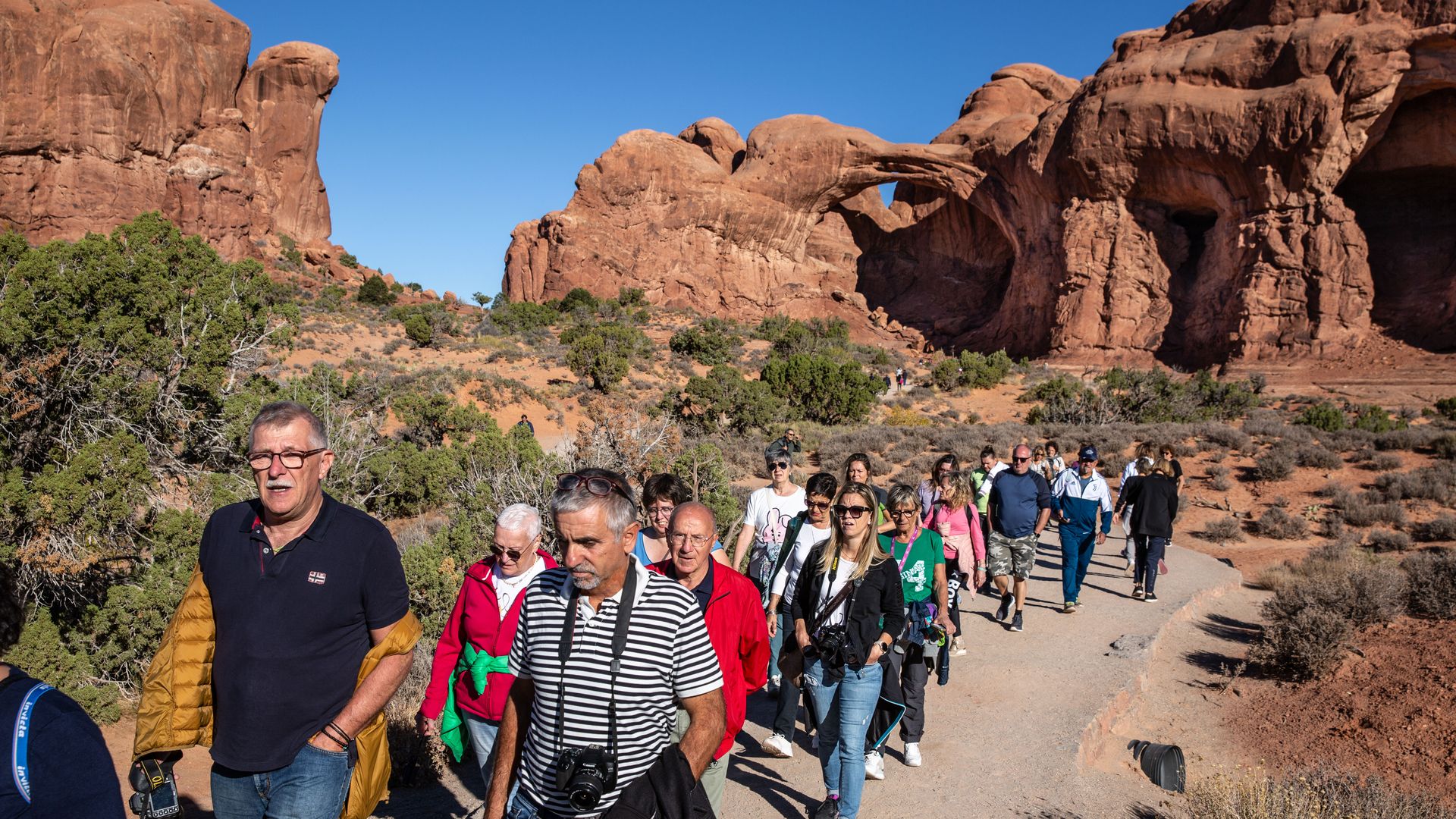 A parade of tourists hiking in Arches National Park