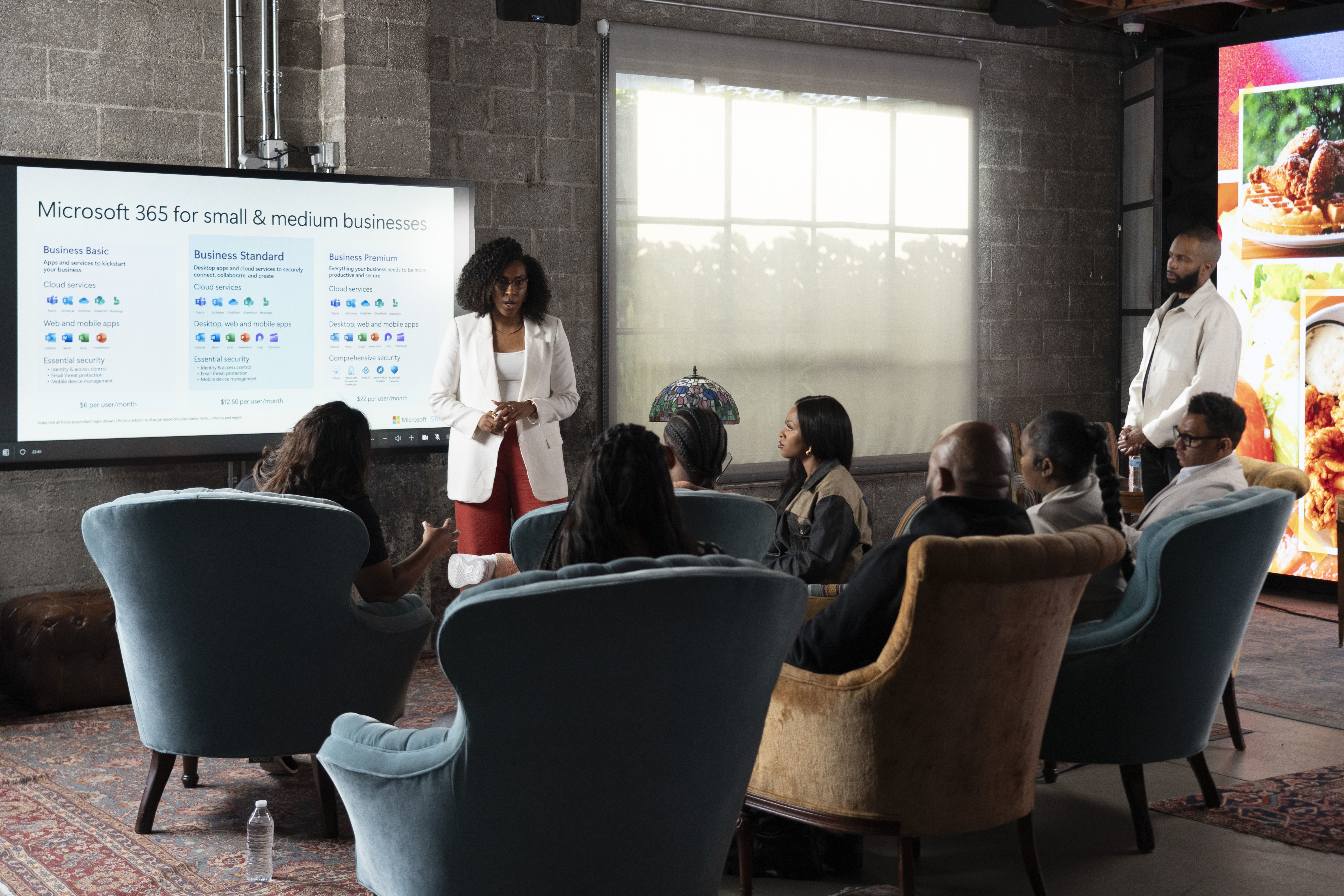 Photos shows people sitting in chairs and watching a presentation from Microsoft.
