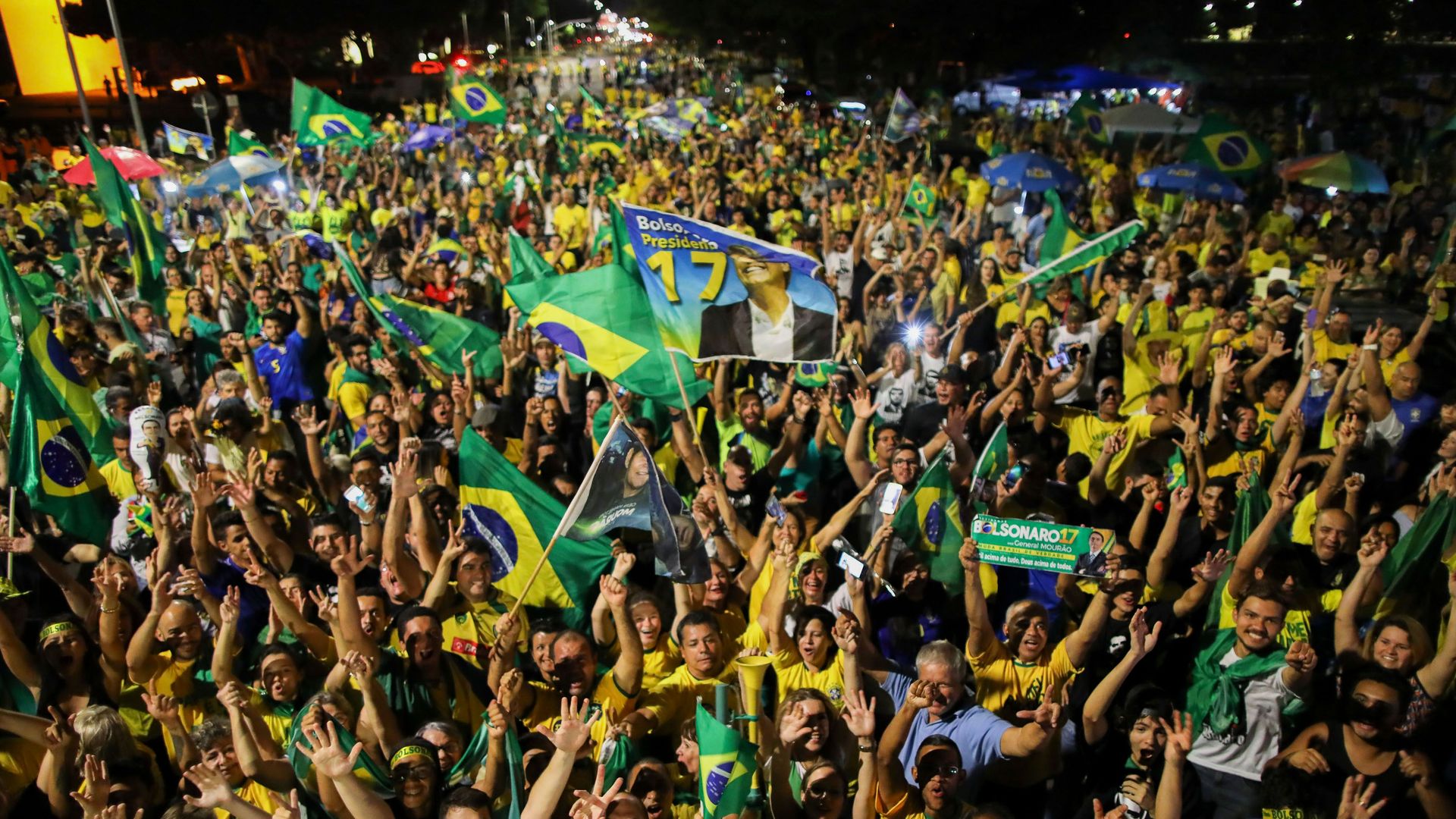 Crowd of cheering people holding Brazilian flags
