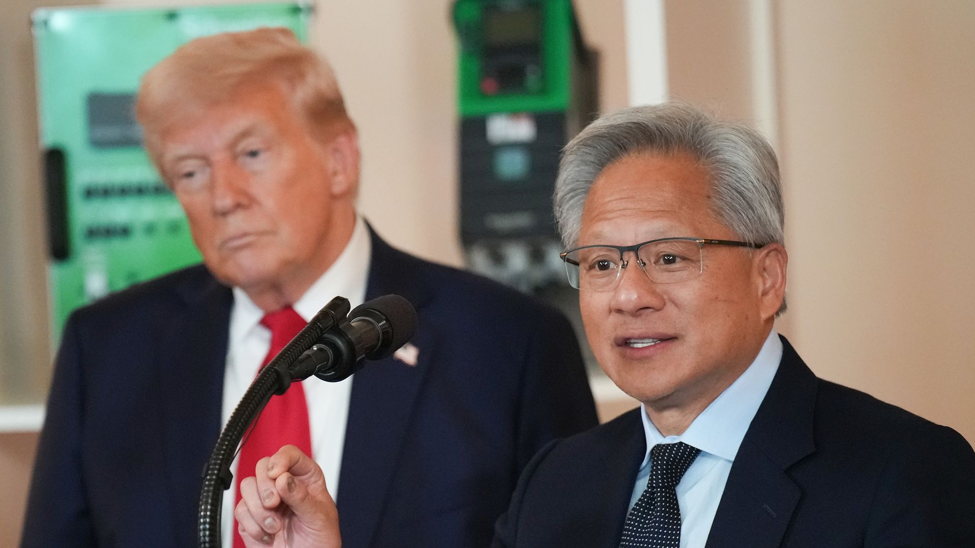 President Trump stands beside Nvidia CEO Jensen Huang as Huang speaks at a White House event.