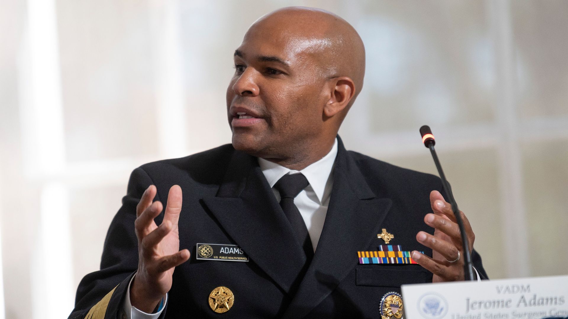 Surgeon General sits in front of a microphone