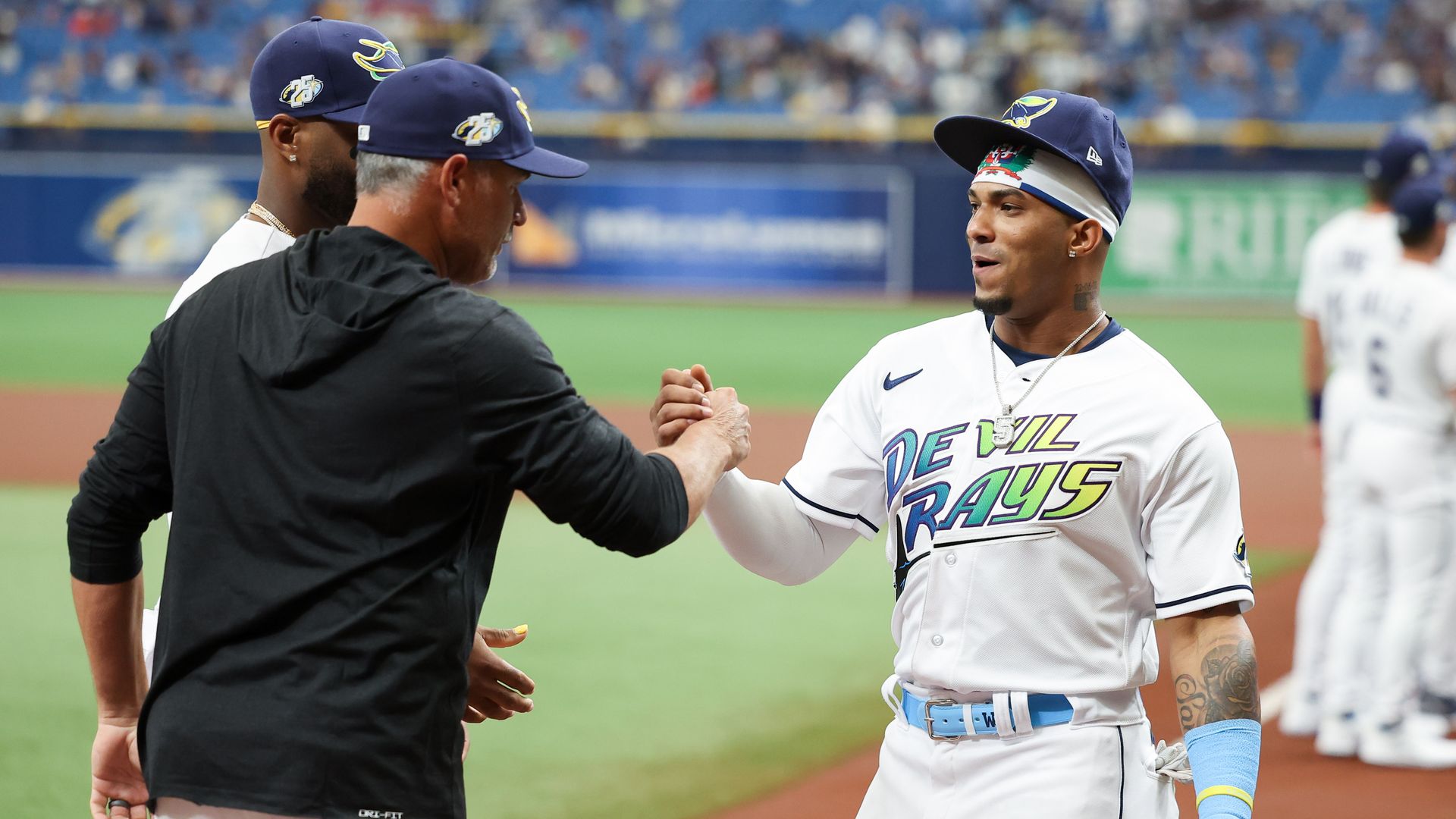 Wander Franco of the Tampa Bay Rays greets Manager Kevin Cash wearing a throwback Devil Rays jersey.