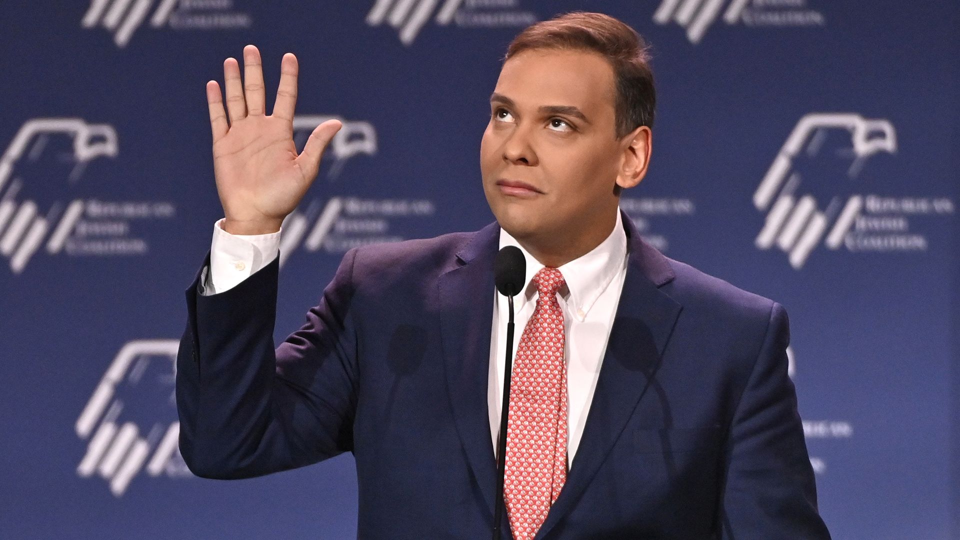 George Santos raises his right hand while speaking