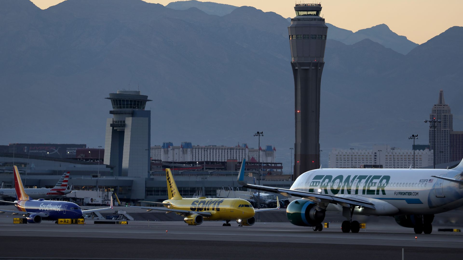 Airplanes at airport including a Frontier Airlines plane