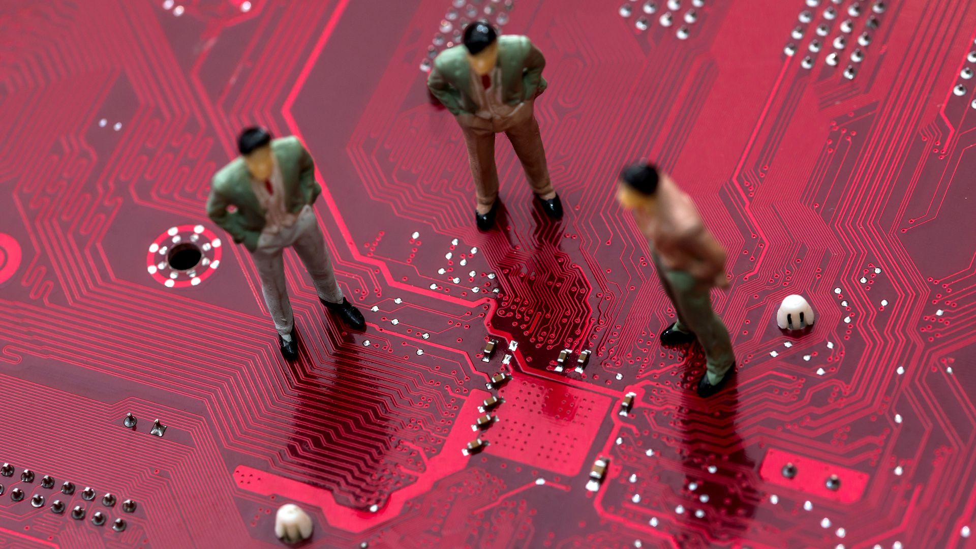 Illustration of three toy men standing on a red motherboard