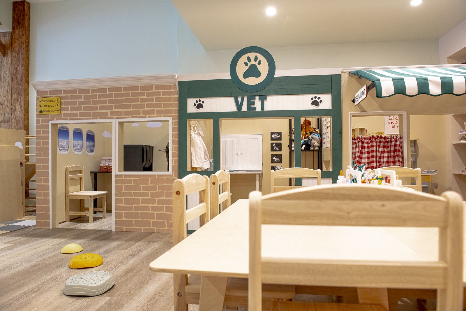A photo showing a children's play space with a faux airport, veterinarian's office and restaurant.