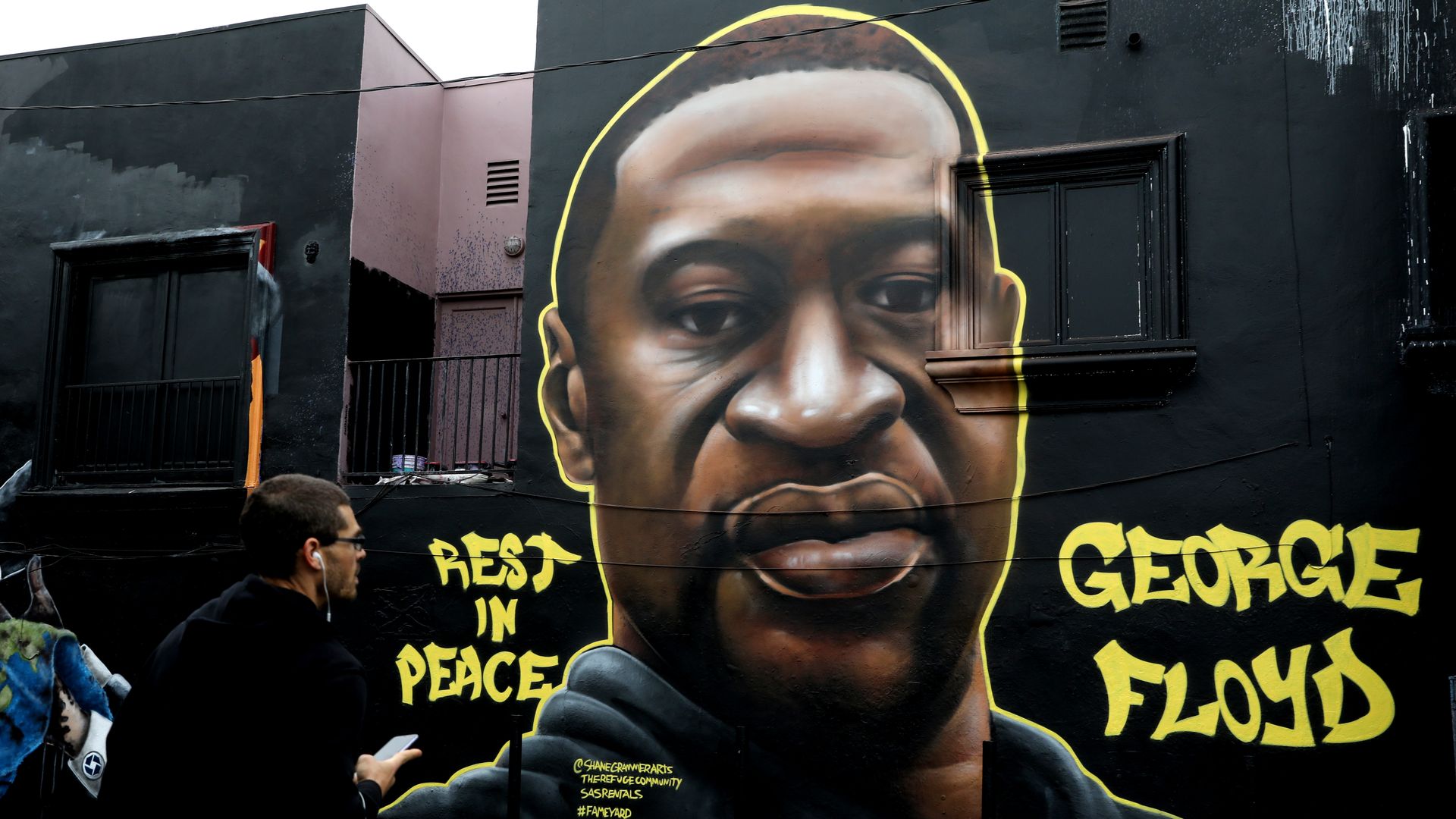 A mural of George Floyd is seen on the side of a building with the words "rest in peace" painted