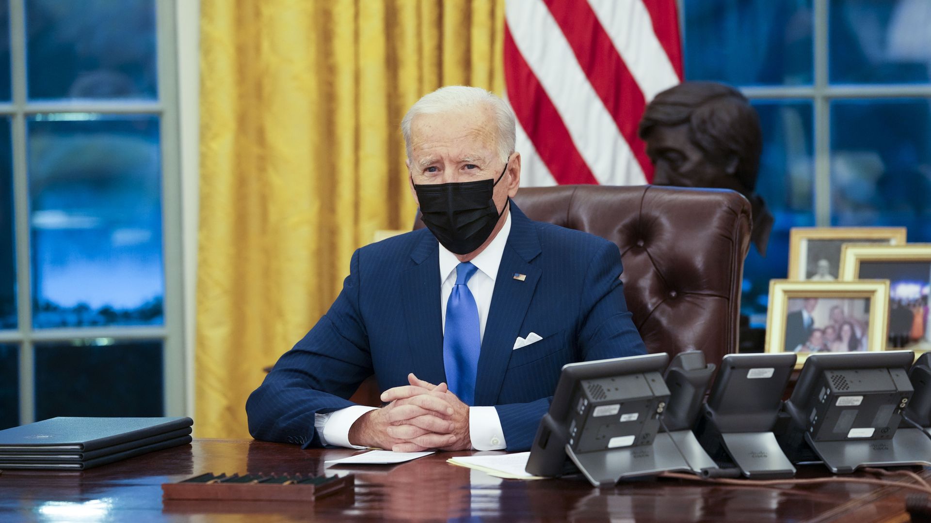 Picture of Joe Biden sitting on his desk in the Oval Office