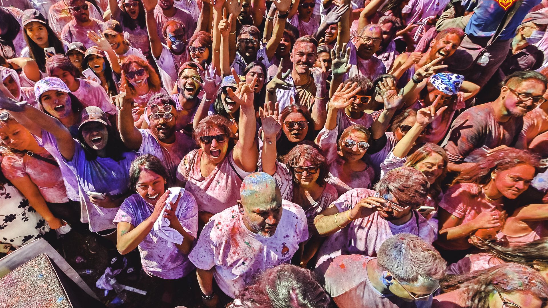 Photo of dozens of people  wearing white shirts doused in color. 