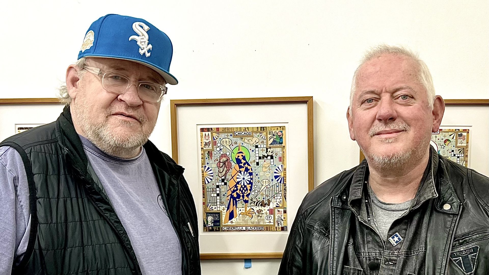 Photo of two guys standing in front of a painting in a gallery. 
