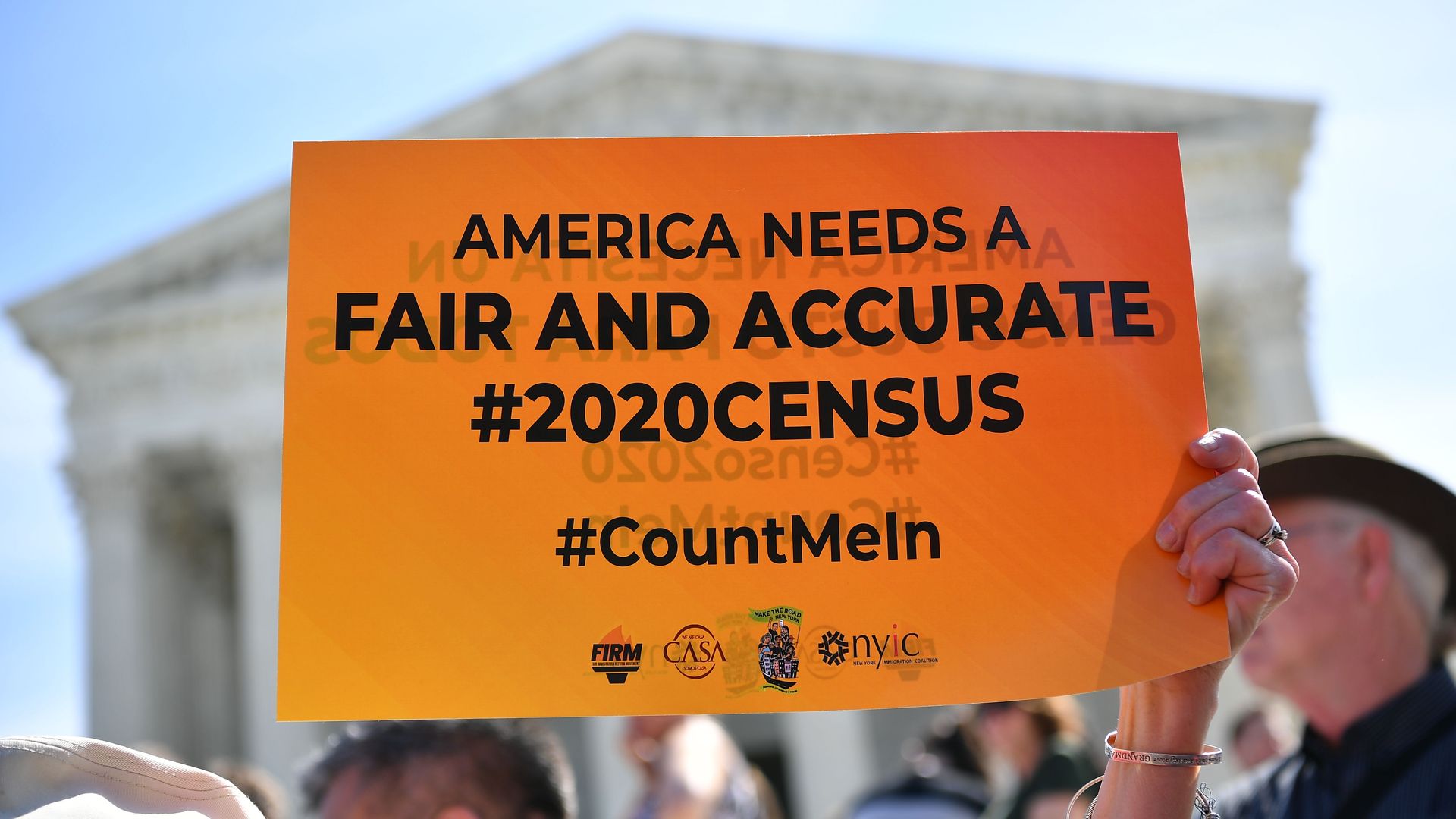 A protester hoists a sign calling for a fair and accurate 2020 Census on the steps of the U.S. Supreme Court at an April rally.