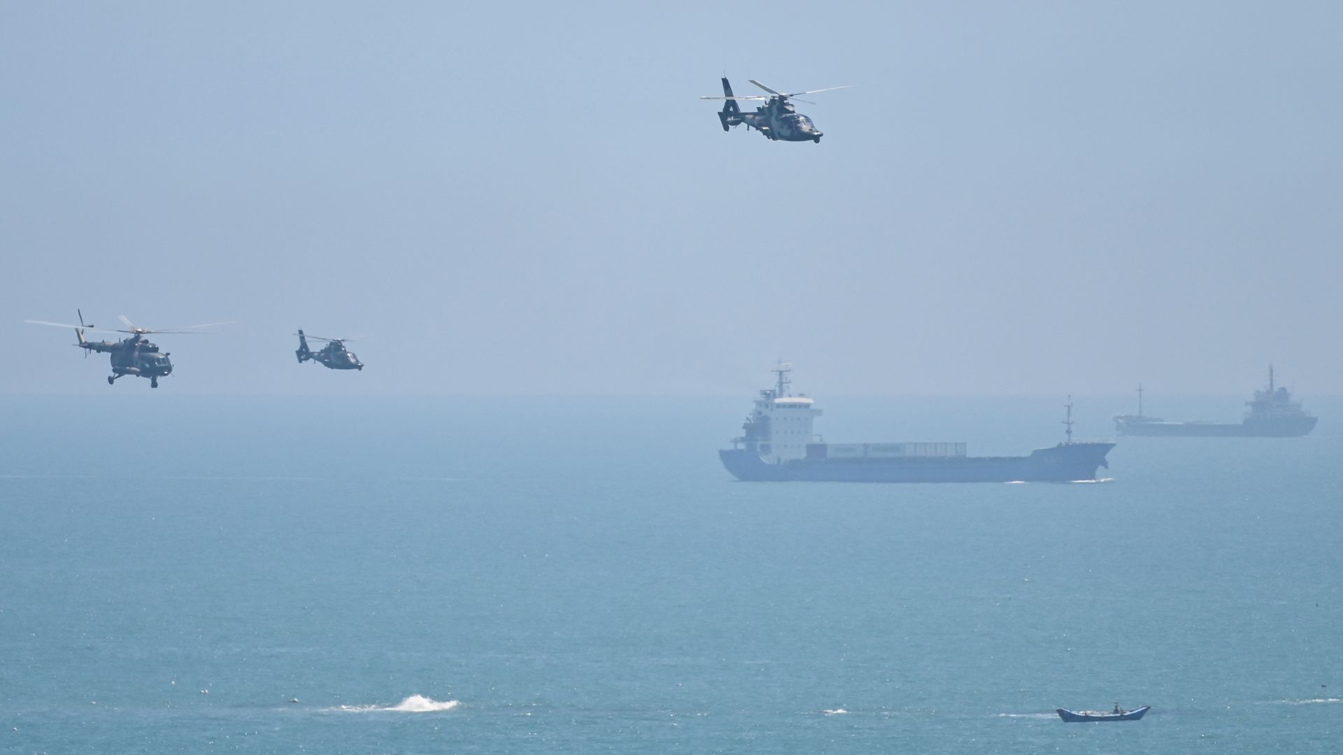 Three Chinese military helicopters fly past two ships in a blue sky over a blue sea near Pingtan island, one of mainland China's closest point from Taiwan, in Fujian province on Aug. 4, 2022.
