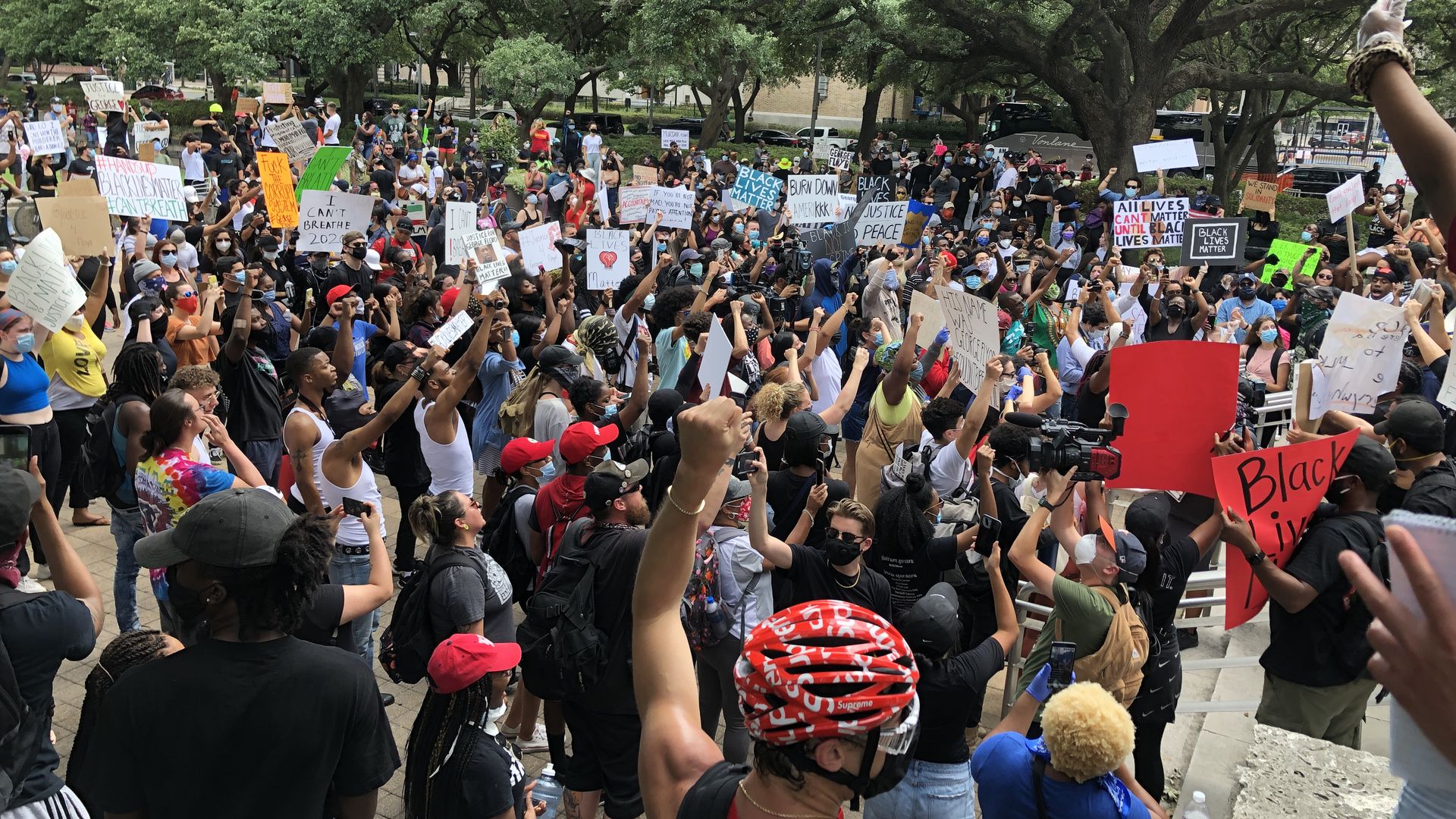 A crowd of Black Lives Matter protestors in 2020 raise their fists in the air.