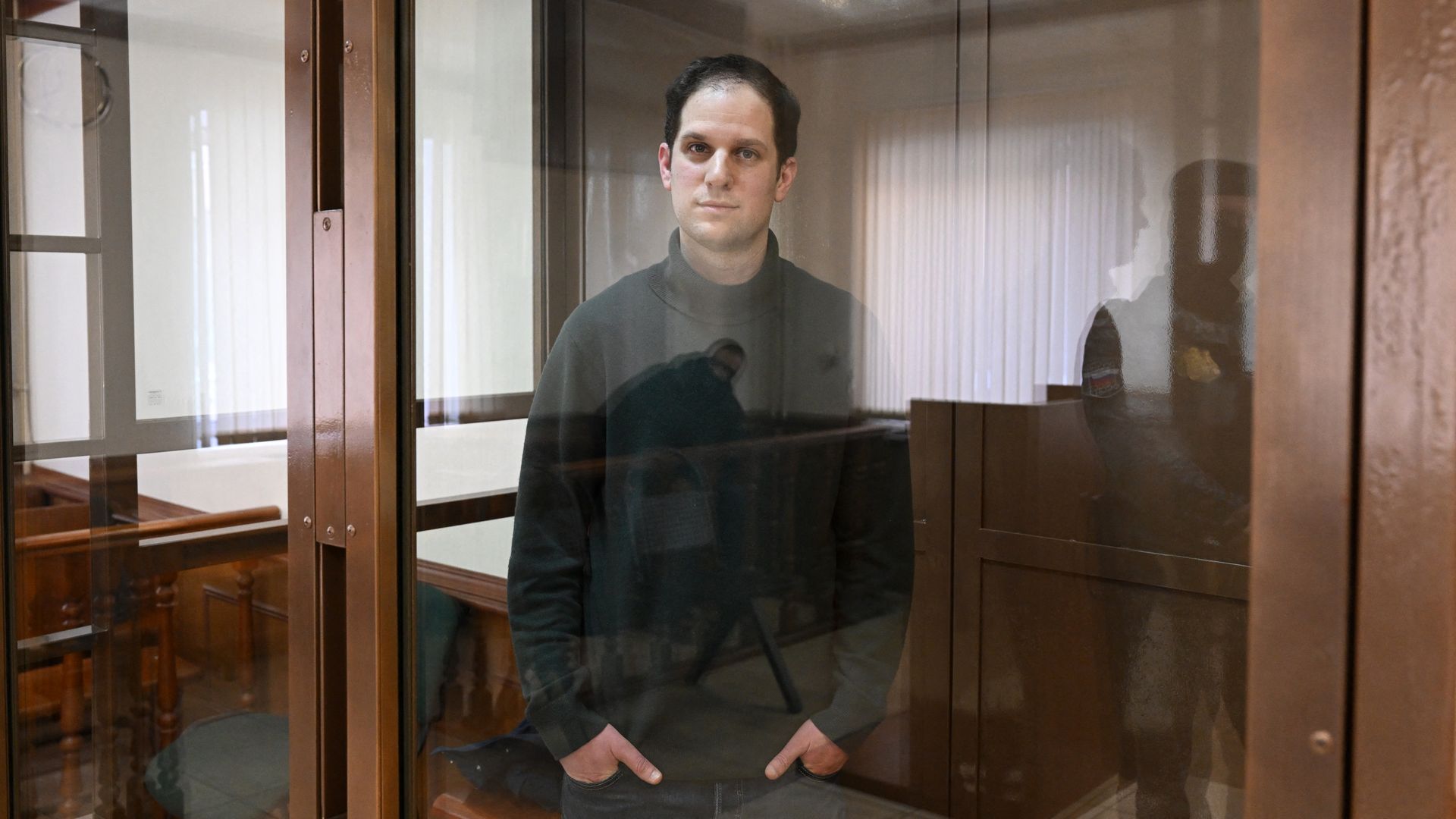 Evan Gershkovich, arrested on espionage charges, looks out from inside a defendants' cage before a hearing to consider an appeal on his extended pre-trial detention, at the Moscow City Court in Moscow on February 20, 
