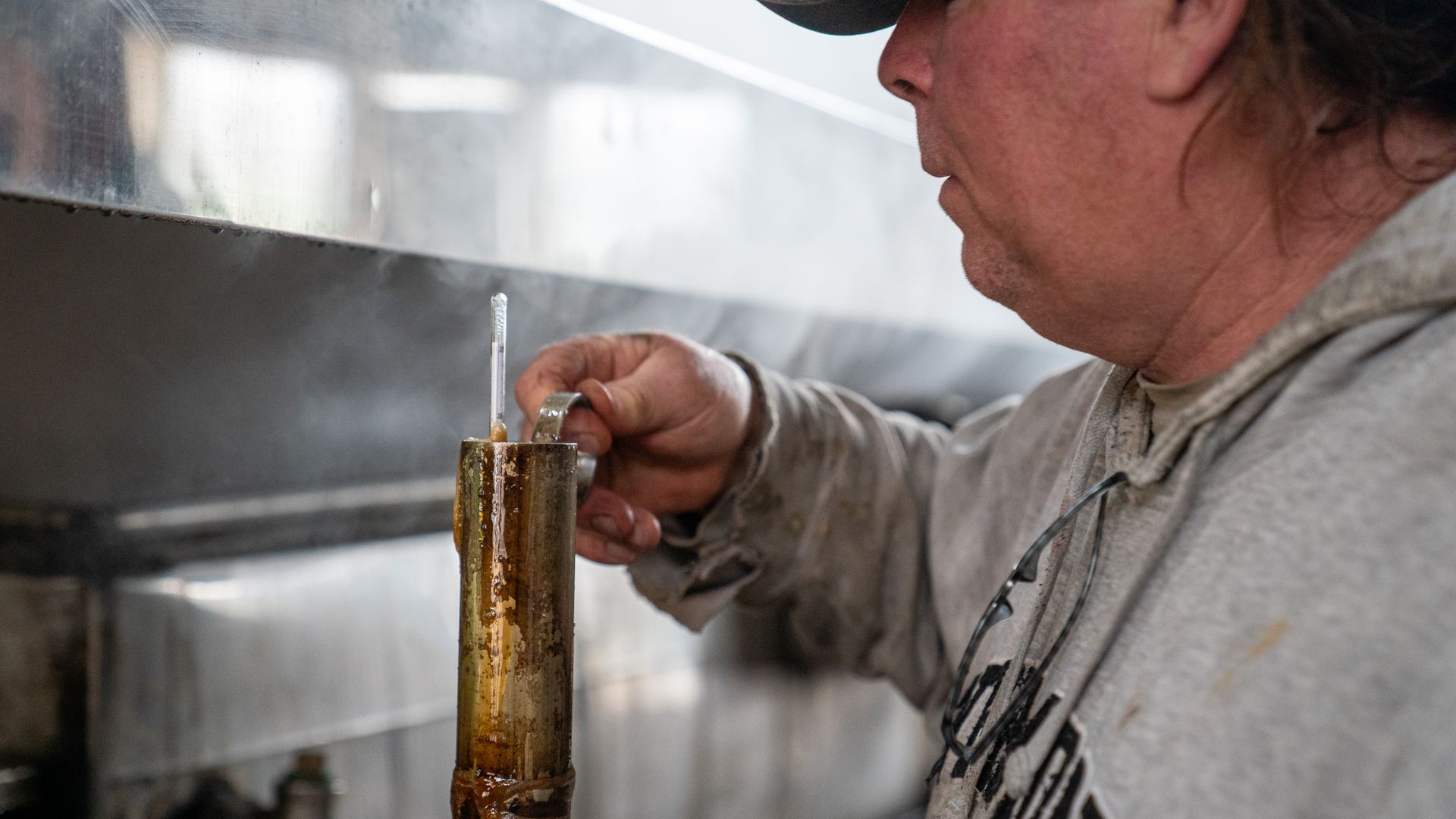 A person holds a metal cylinder full of maple syrup