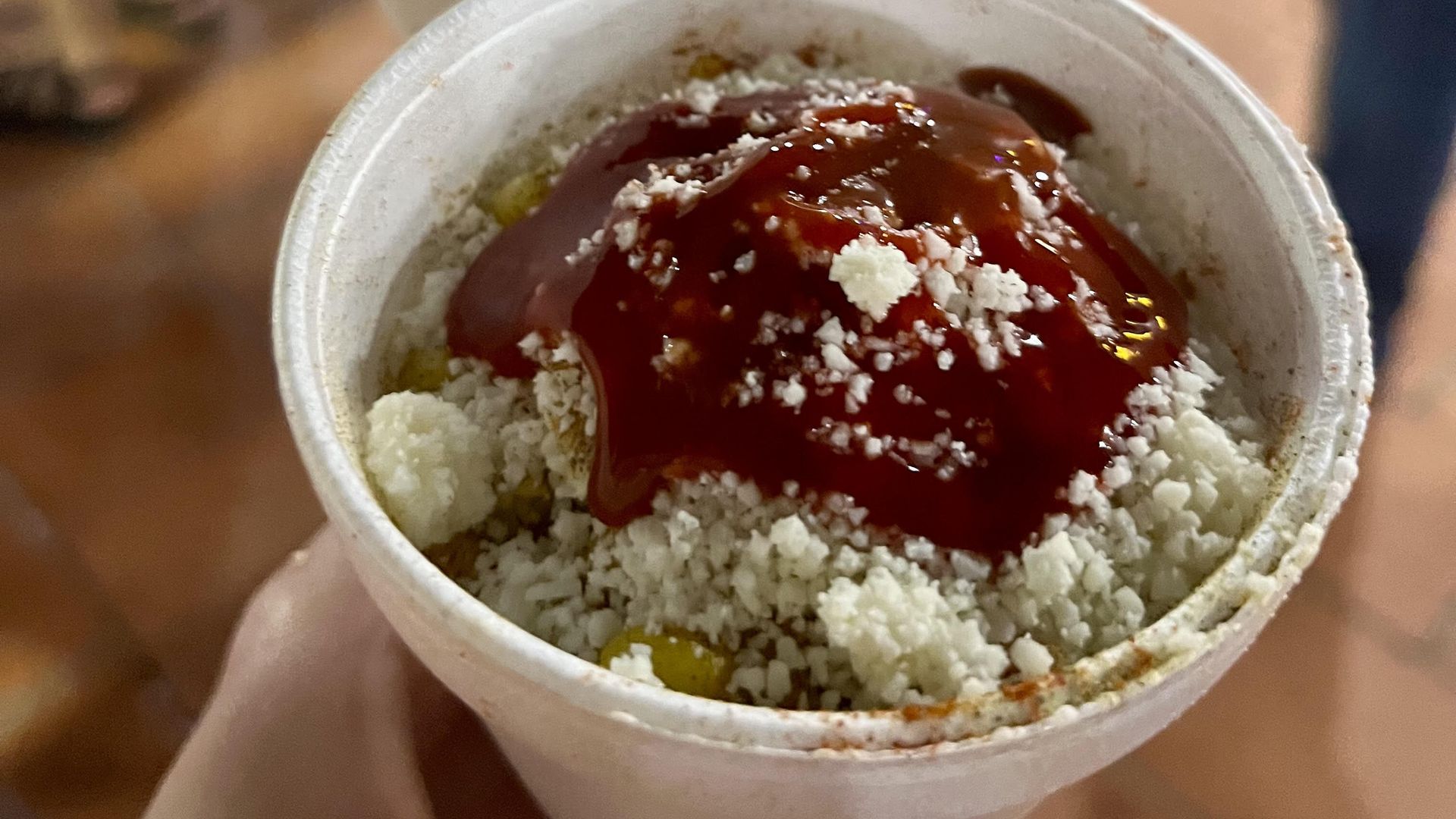 A cup filled with corn and toppings. 