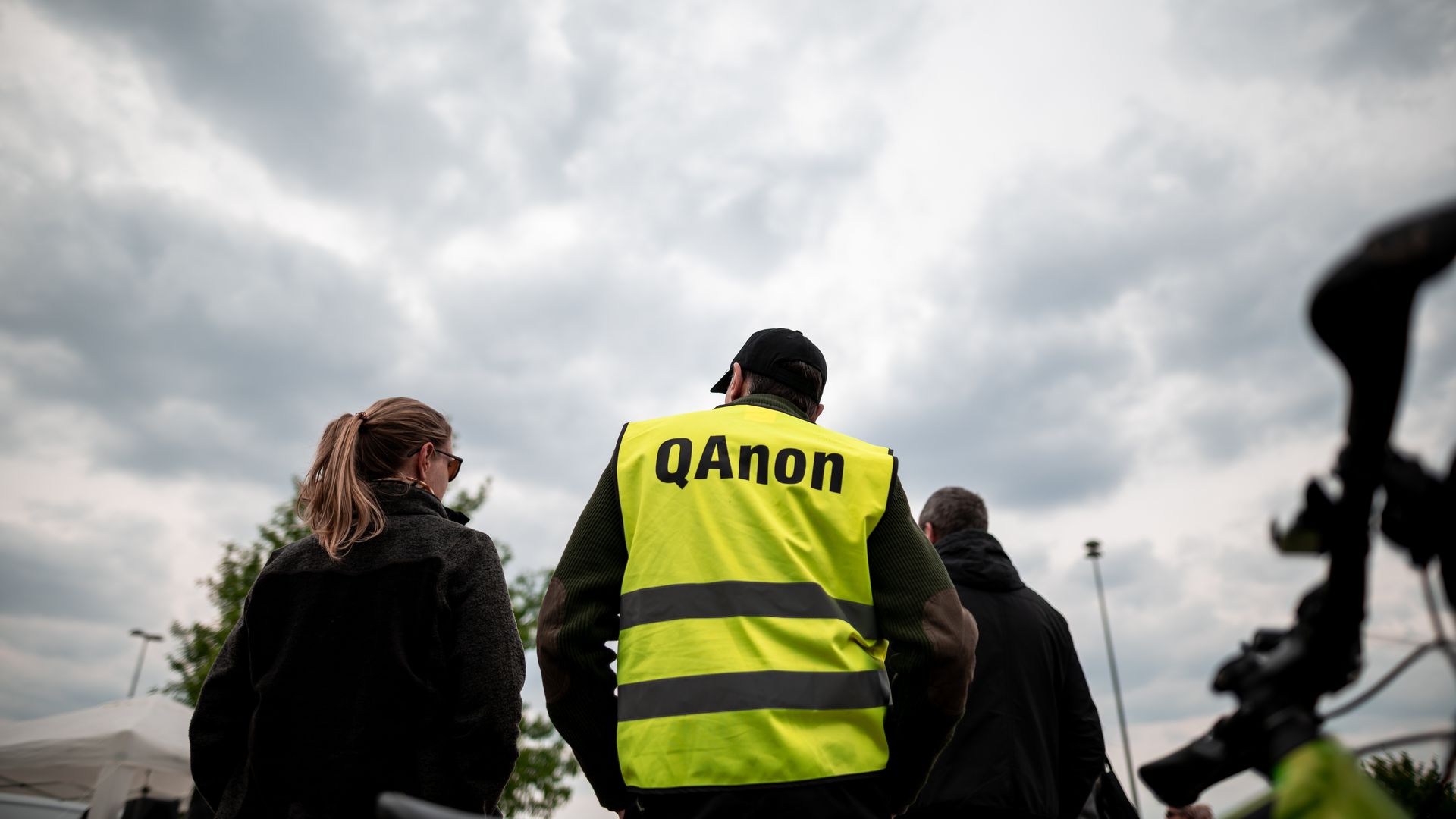 A man wears a bright vest that says "Qanon" while protesting coronavirus measures