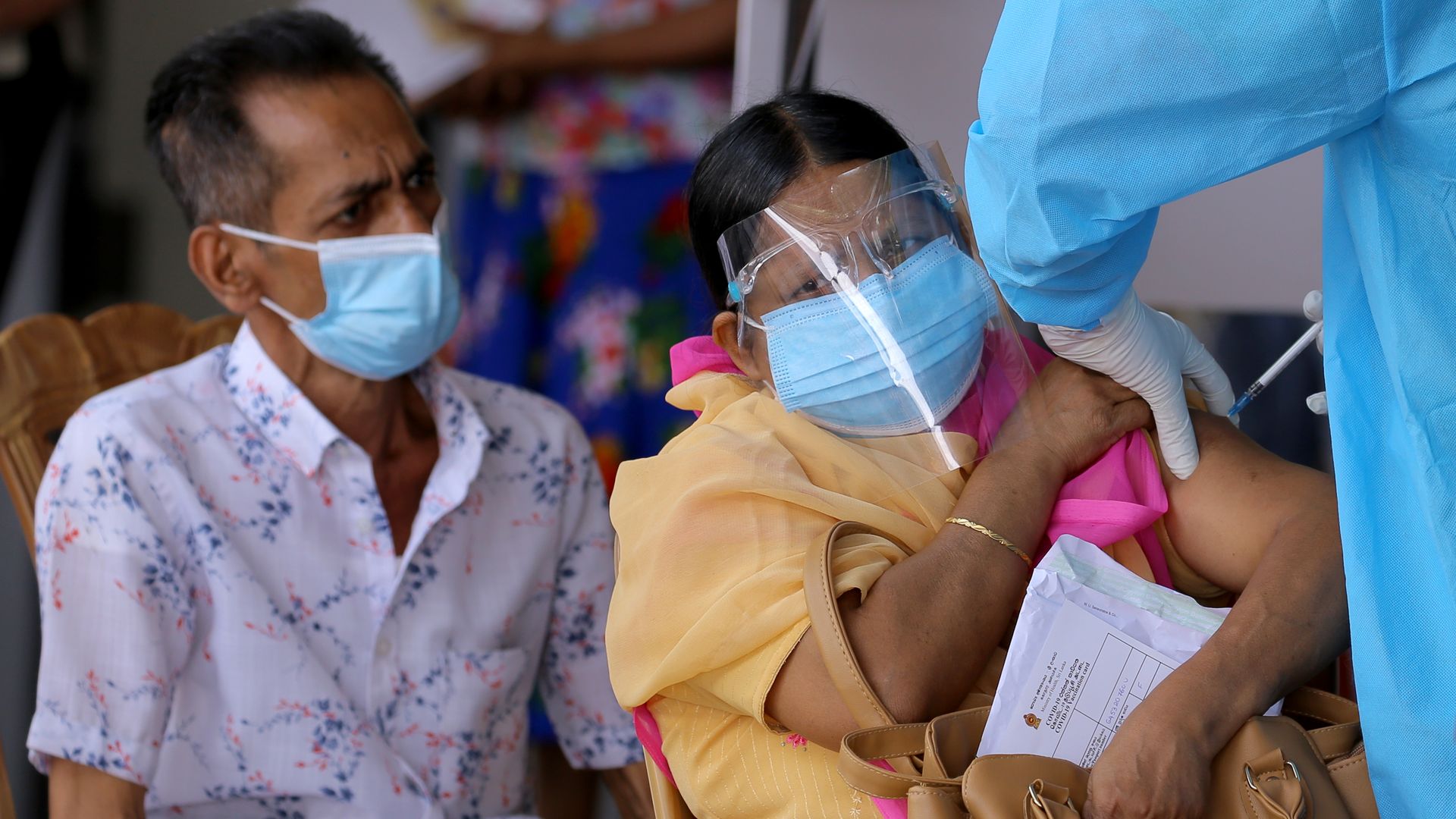 A Sri Lankan woman reacts as she receives a jab at a vaccination center in Colombo, Sri Lanka