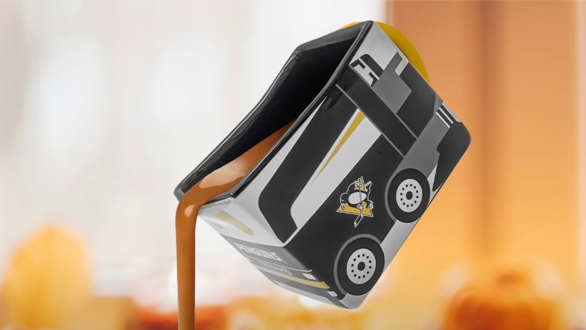 Close-up of a stylized black, white, and gray bus graphic on a tilted rectangular card mounted on a yellow stand, with an orange blurred background.