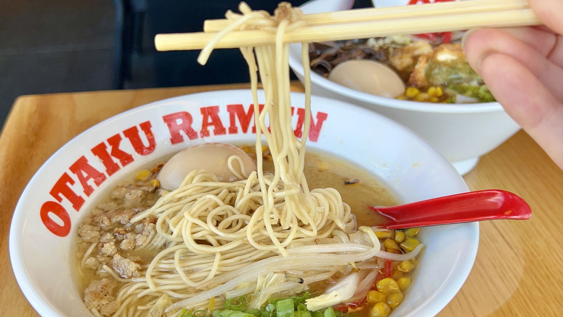 bowl of ramen with a hand holding noodles above