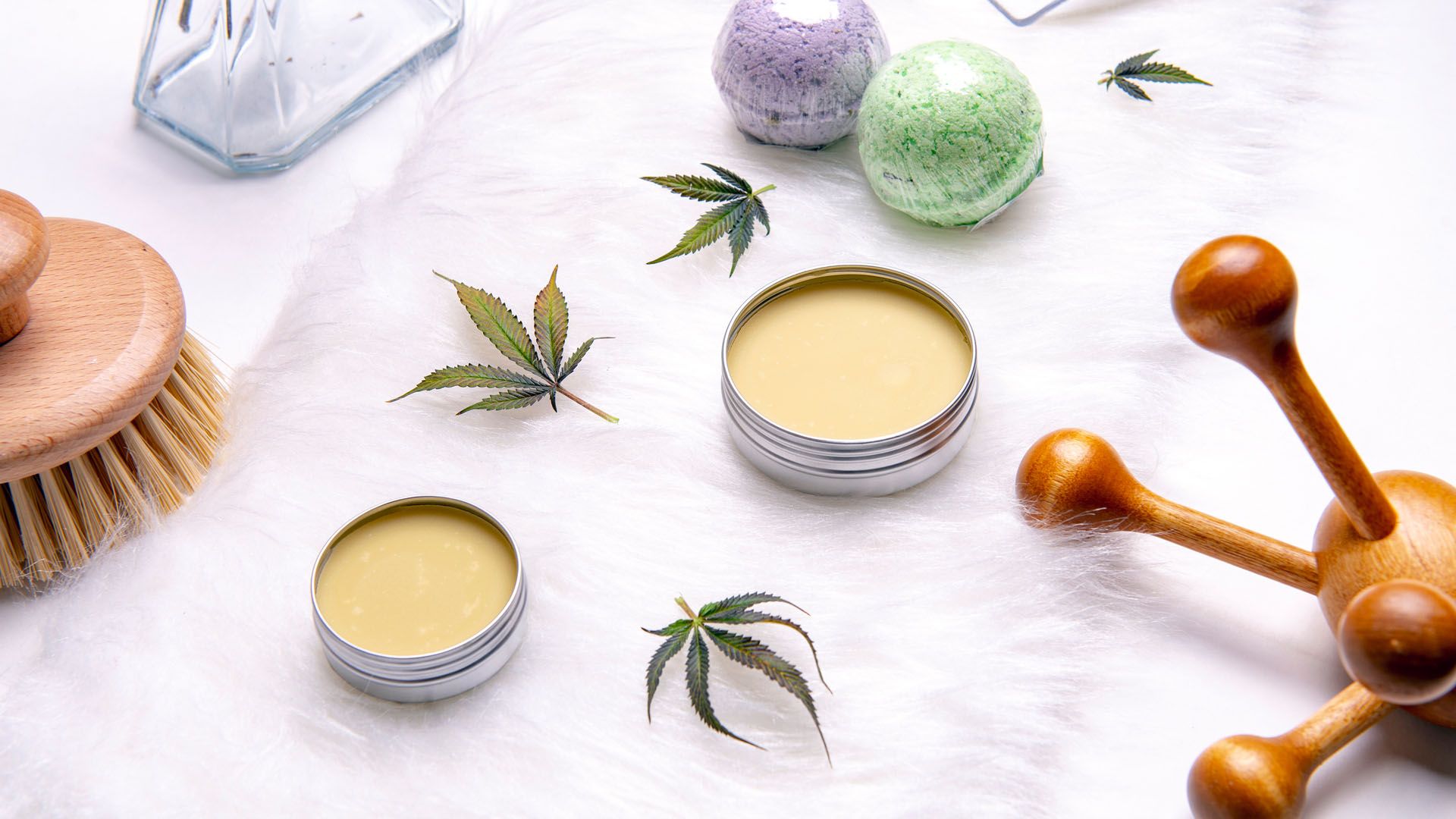 Several lip balms arranged in a pleasing pattern next to cannabis leaves