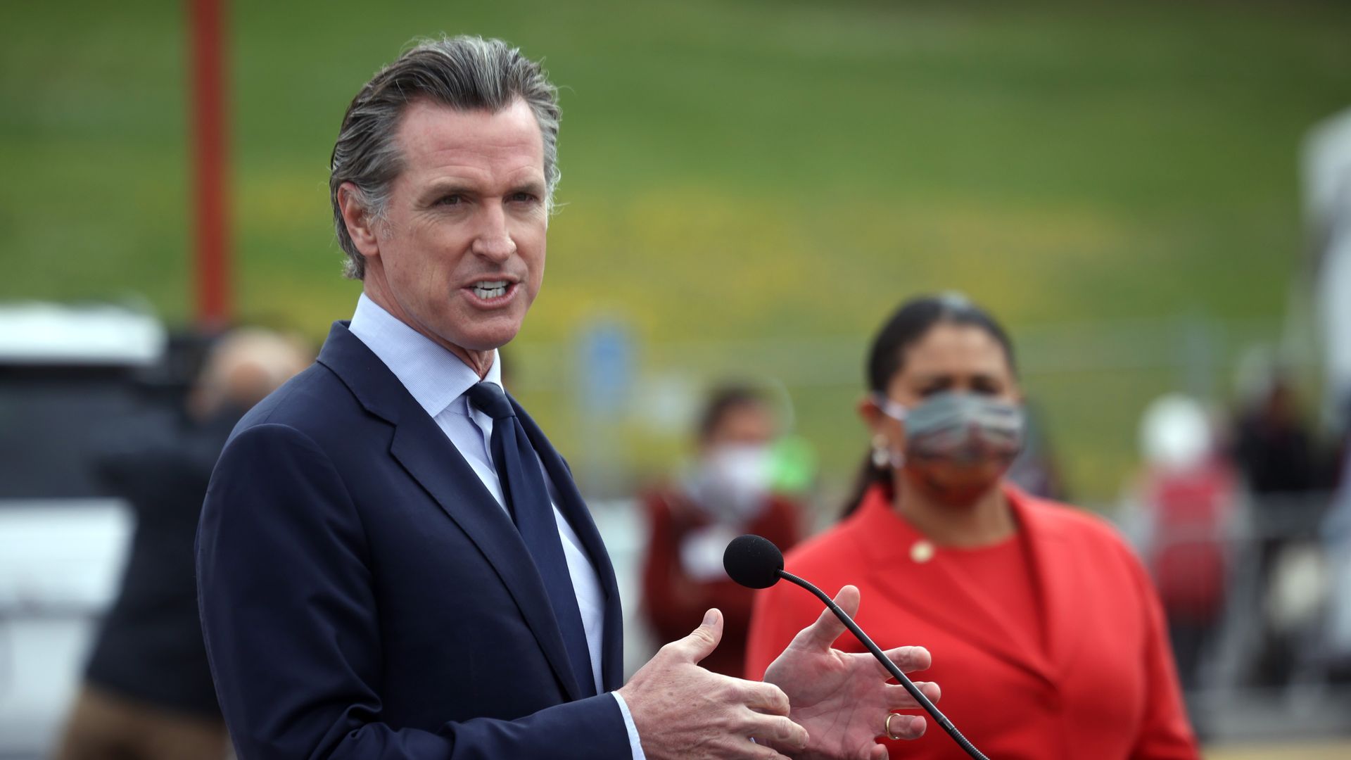 Photo of Gavin Newsom speaking into a mic and gesturing with his hands