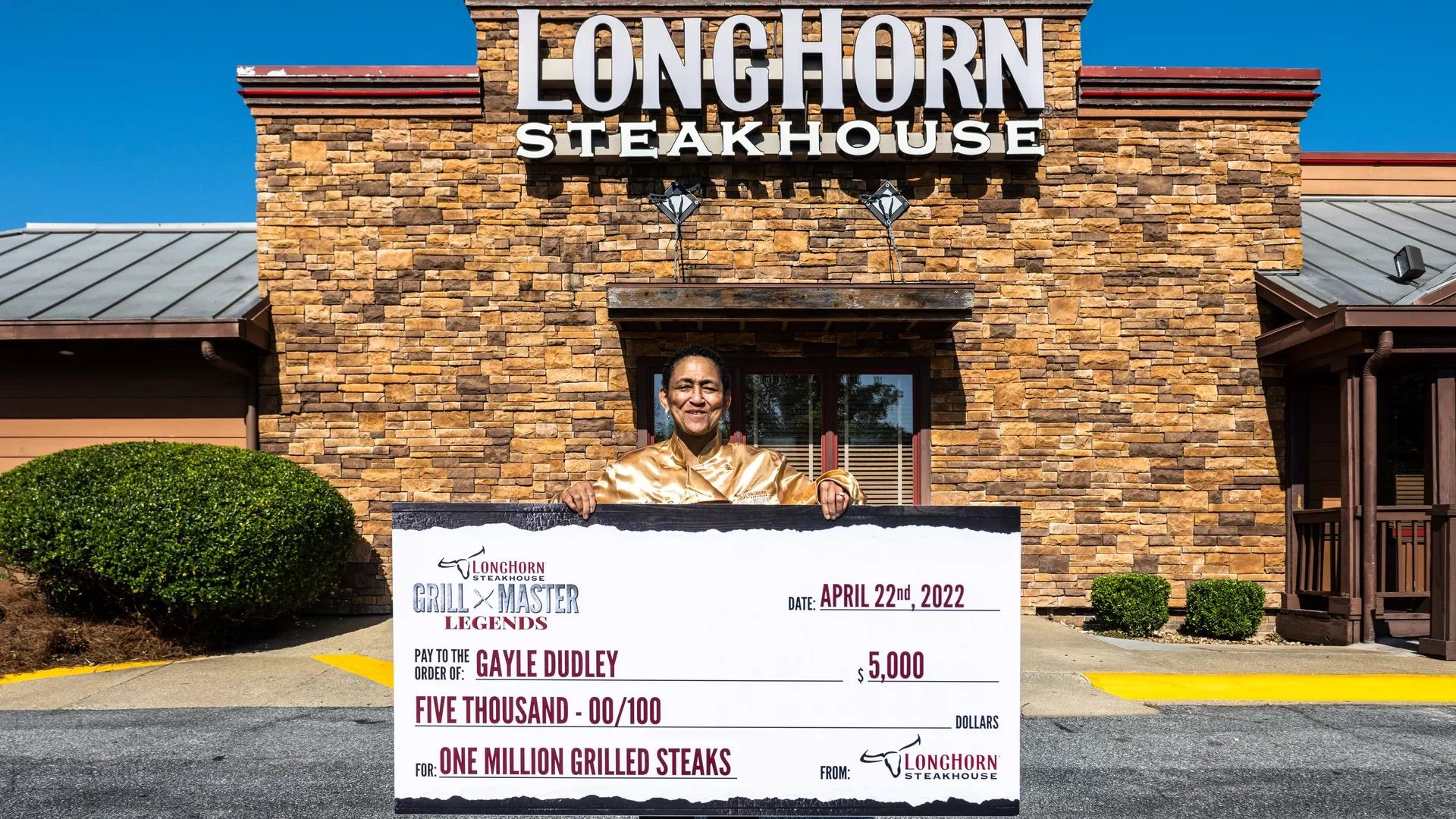 A person holding a giant check she received for grilling 1 million steaks at LongHorn Steakhouse