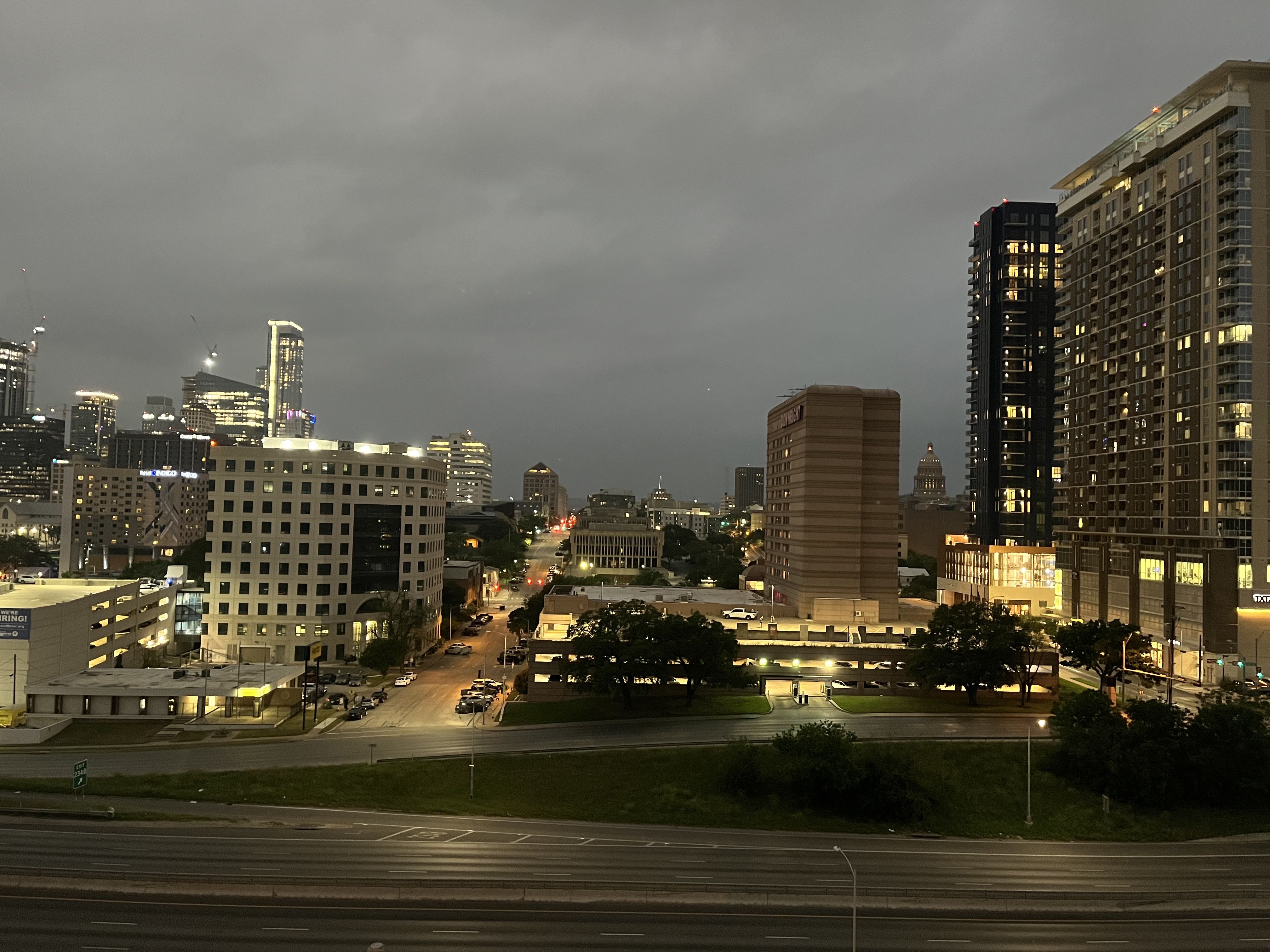 An empty highway in front of the Austin skyline under dark skies