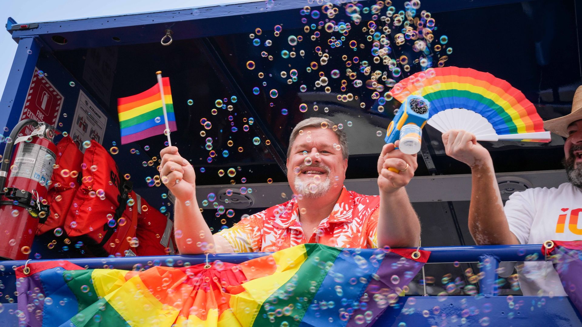 SAN DIEGO, CALIFORNIA, UNITED STATES - 2025/07/19: A joyful man beams from a float decorated with rainbow flags, holding a mini Pride flag and a bubble blower. Surrounded by bubbles and vibrant colors, he radiates celebration and LGBTQ+ pride. Participants marched during the San Diego Pride Parade,