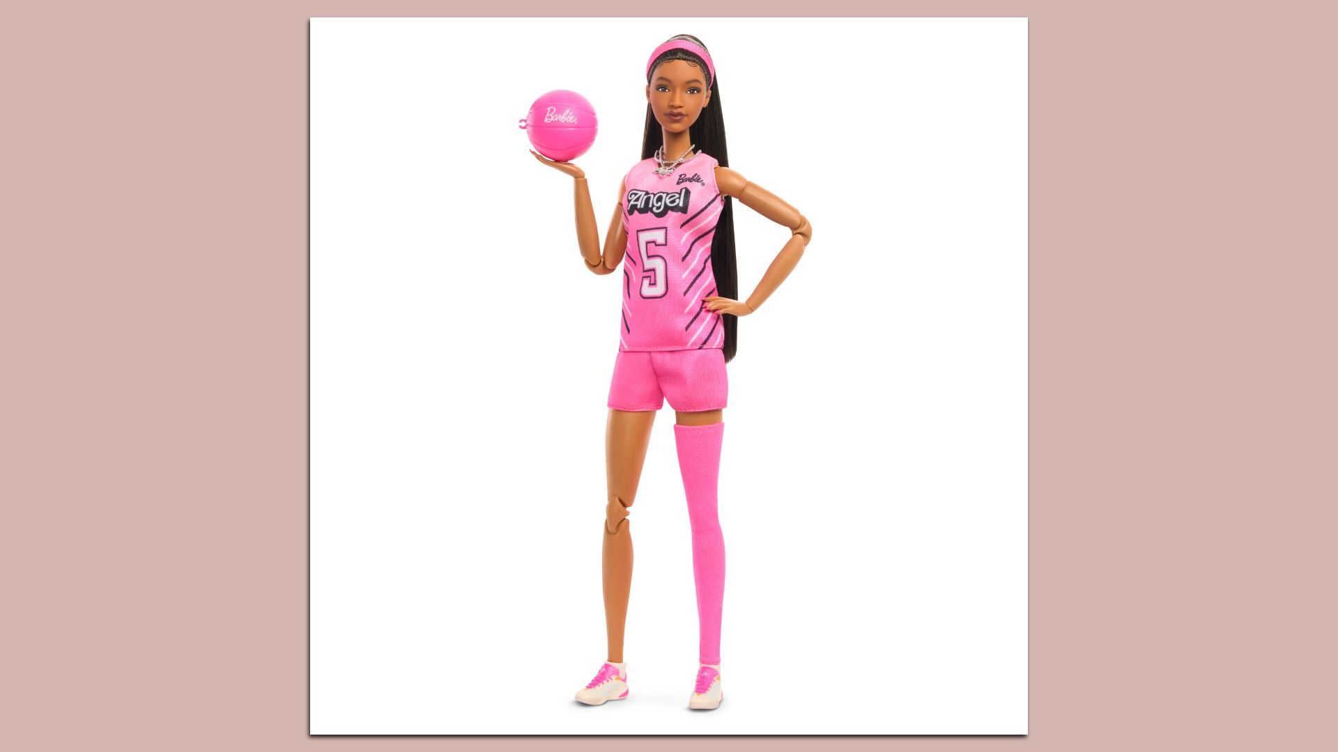 Barbie doll in a pink basketball uniform with the number 5, long black hair, pink headband, standing with one hand on her hip and holding a pink basketball.