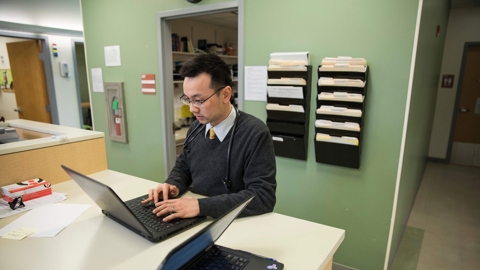 A doctor types on his computer in his office.